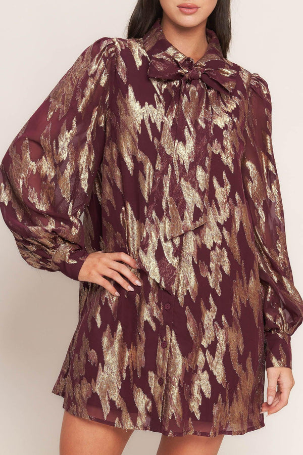 A metallic threaded woven mini dress featuring collar, bow tie, front button down and long sleeve with cuff