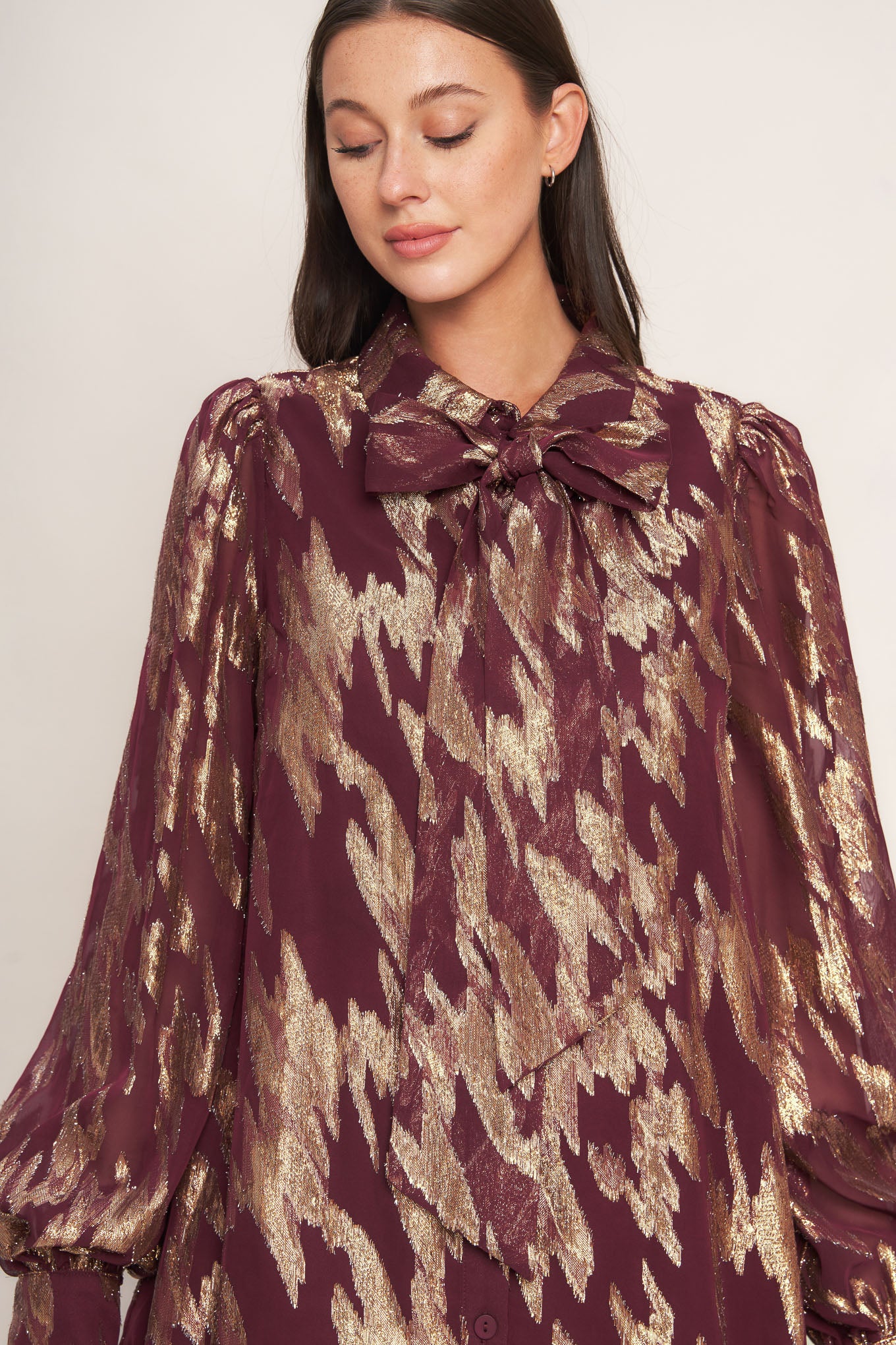 A metallic threaded woven mini dress featuring collar, bow tie, front button down and long sleeve with cuff