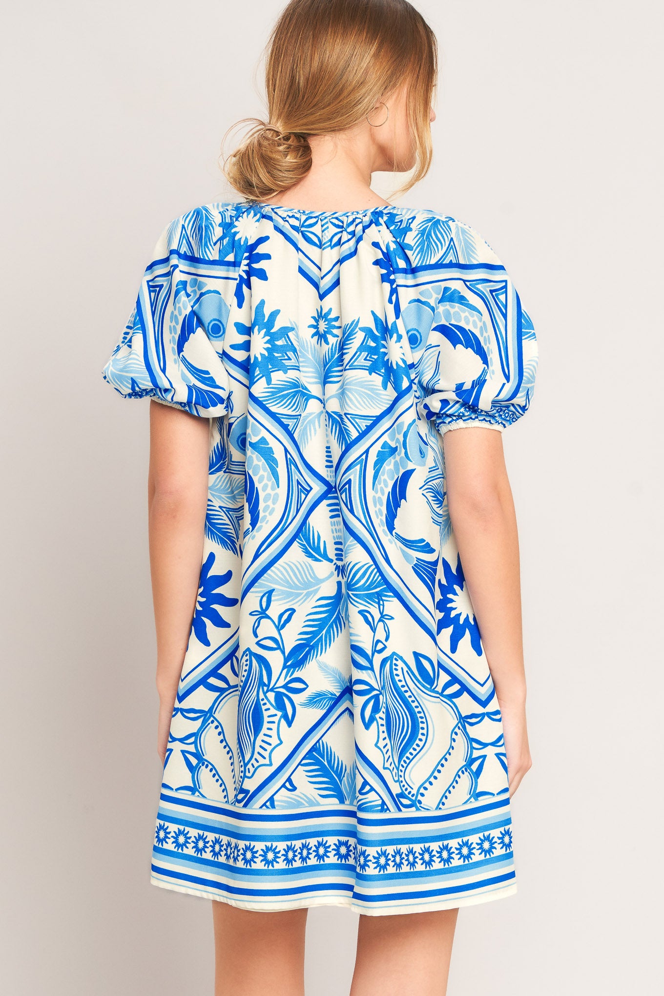 Woman wearing a blue and white patterned dress on a plain background
