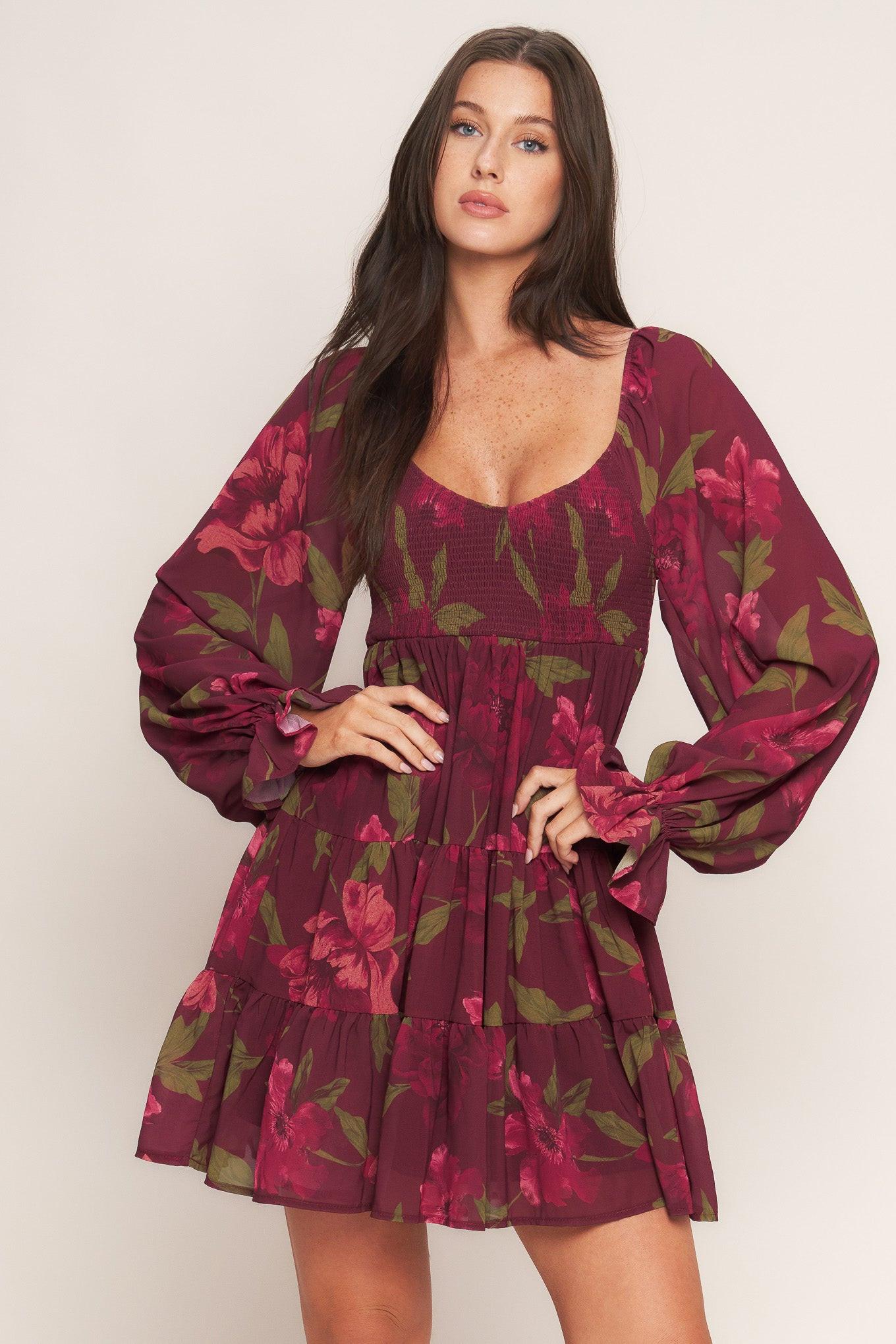 A printed woven mini dress featuring U neckline, smocked bodice, long sleeve with ruffled cuff and tiered skirt