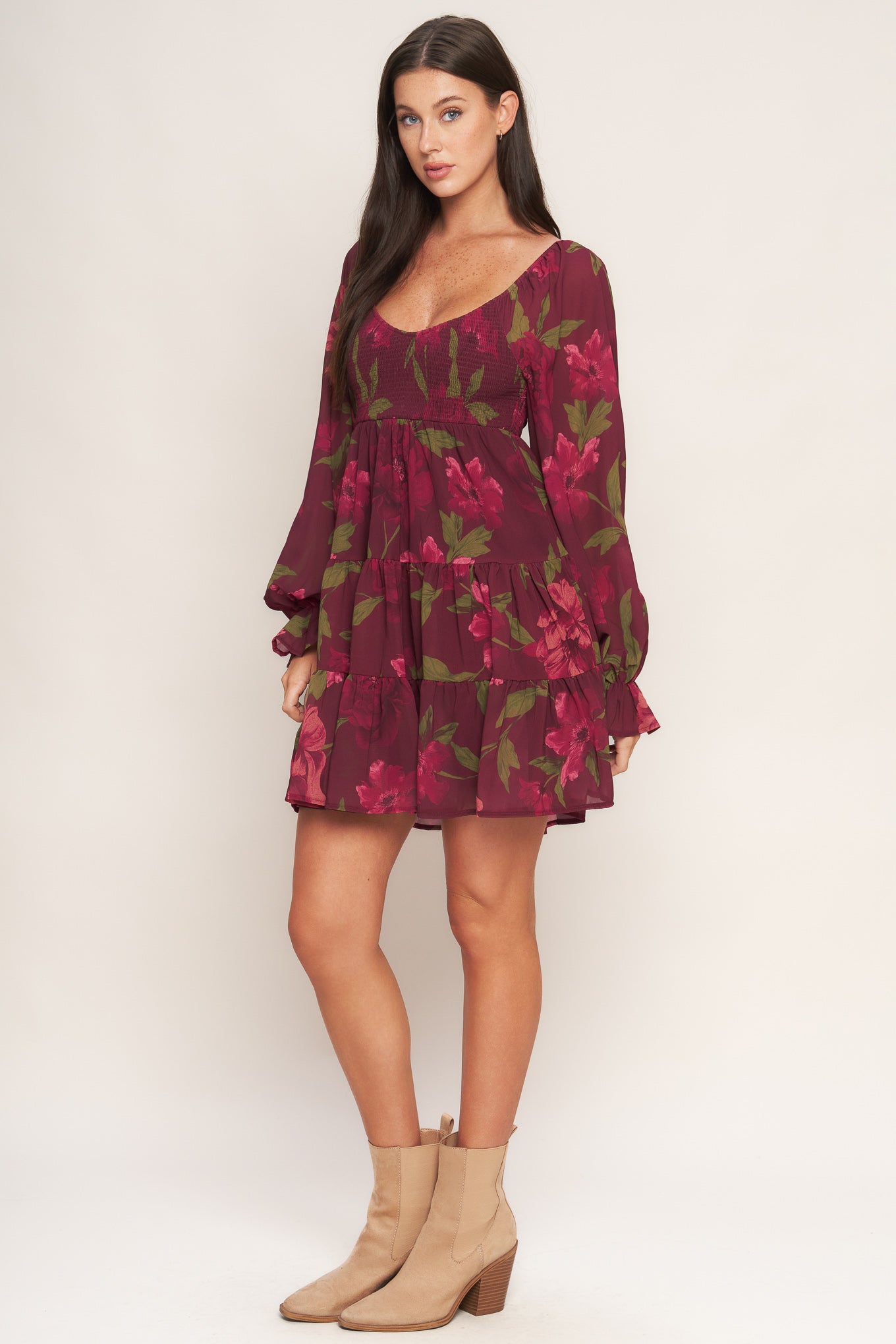 A printed woven mini dress featuring U neckline, smocked bodice, long sleeve with ruffled cuff and tiered skirt