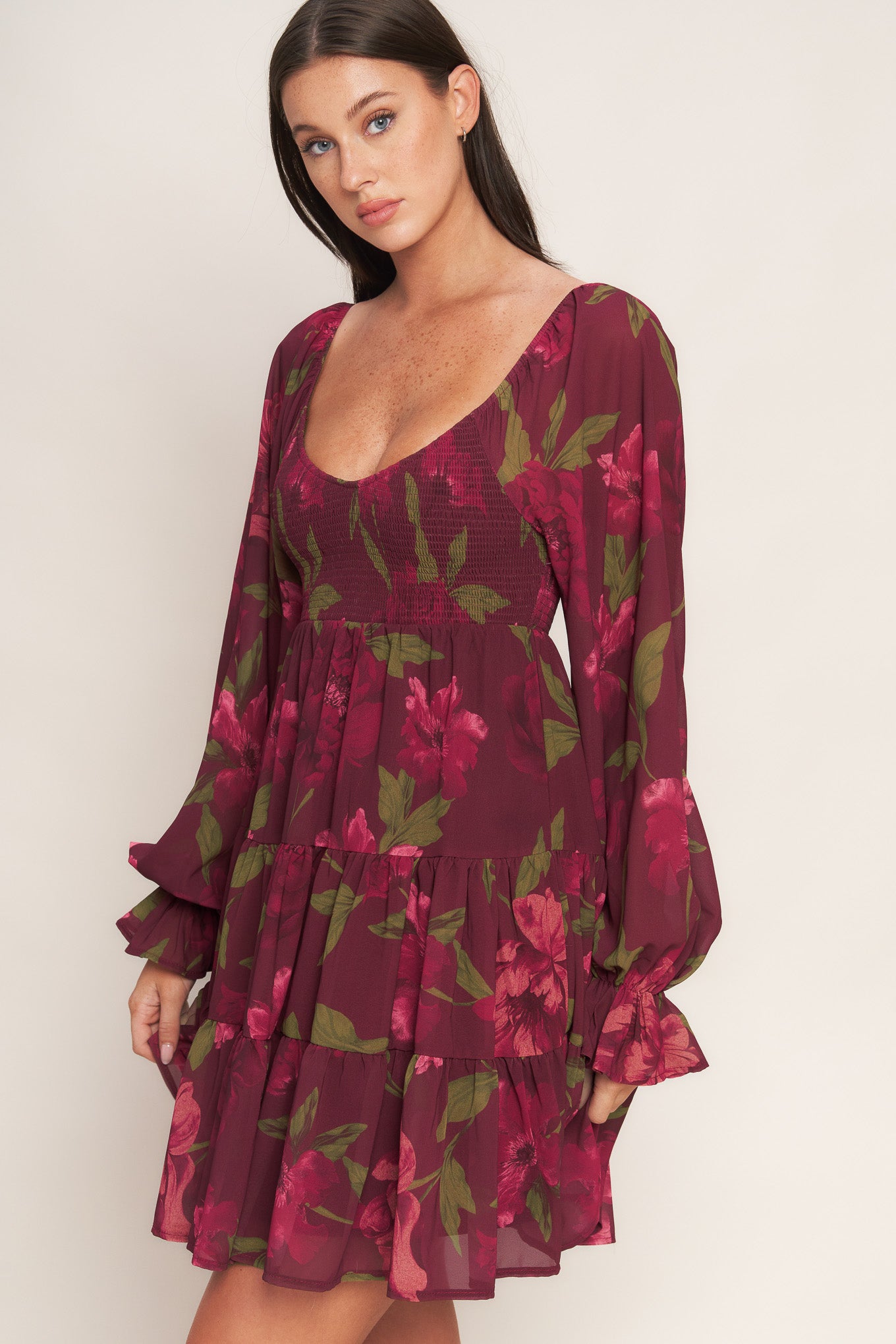 A printed woven mini dress featuring U neckline, smocked bodice, long sleeve with ruffled cuff and tiered skirt