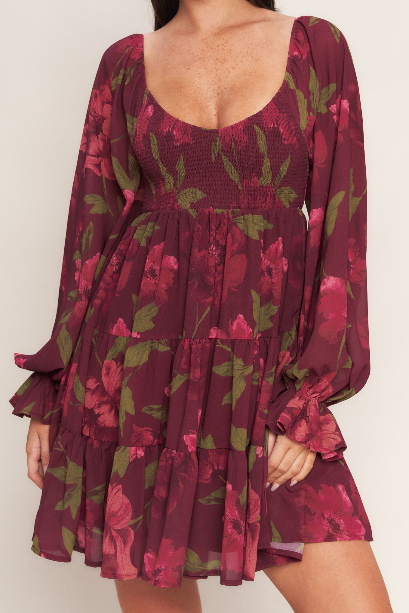 A printed woven mini dress featuring U neckline, smocked bodice, long sleeve with ruffled cuff and tiered skirt
