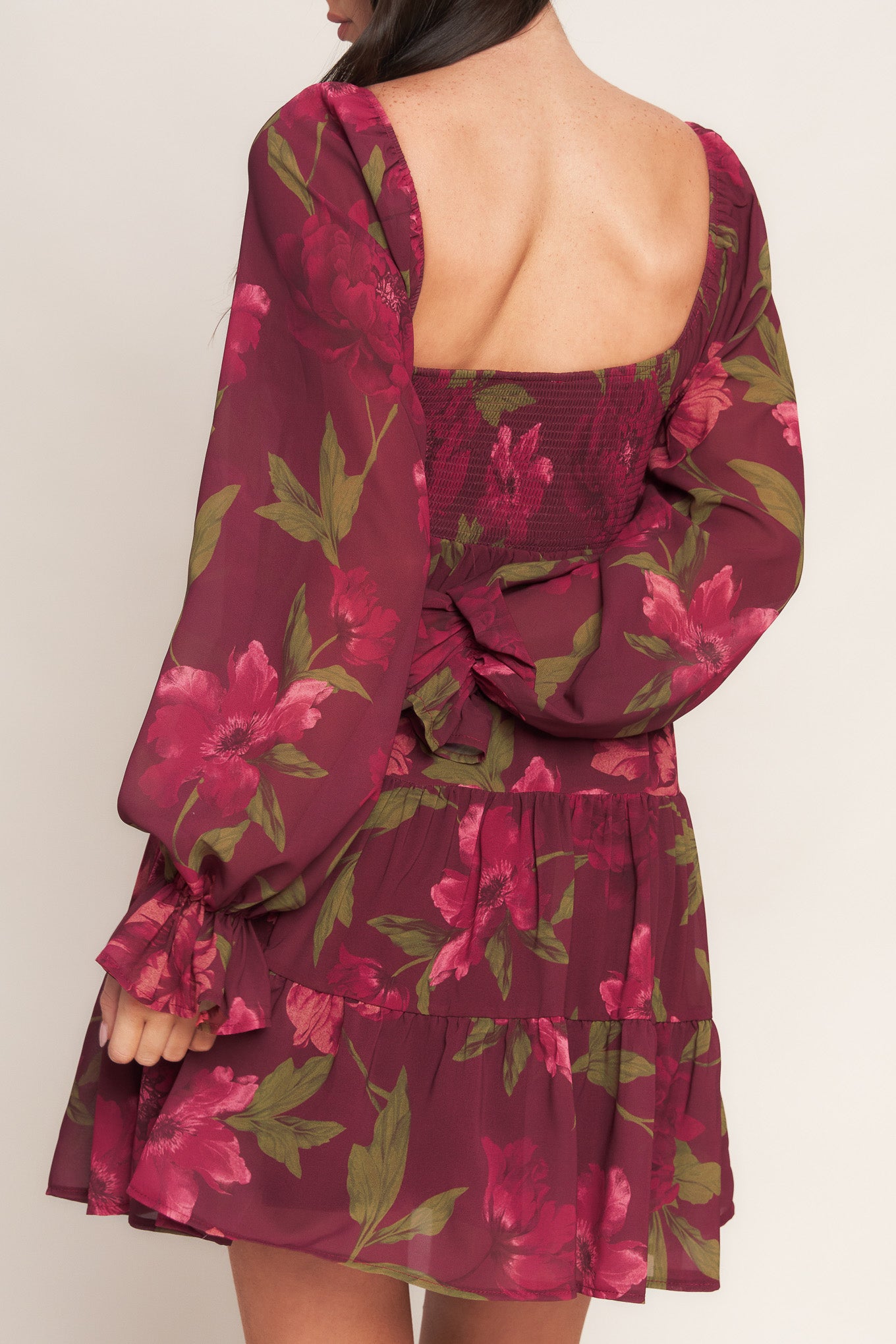 A printed woven mini dress featuring U neckline, smocked bodice, long sleeve with ruffled cuff and tiered skirt