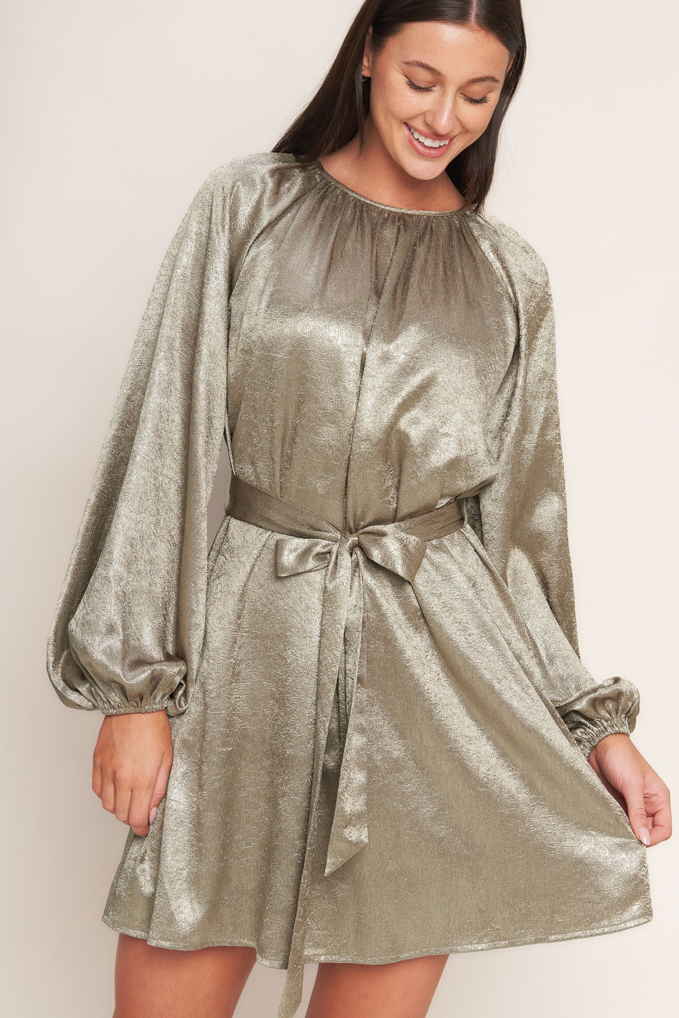 A foiled woven mini dress featuring round neckline, long sleeve, self sash tie and back neck button closure