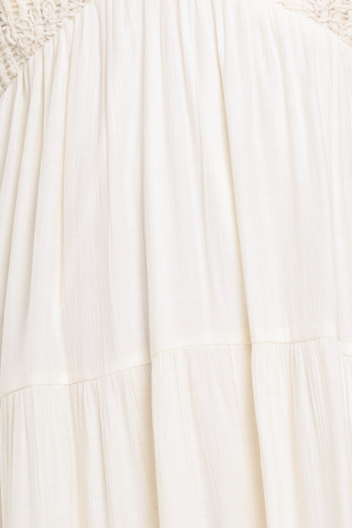 Woman wearing a cream flowy maxi dress featuring lace bodice, shoulder tie, tier body and smocked back bodice | Flying Tomato