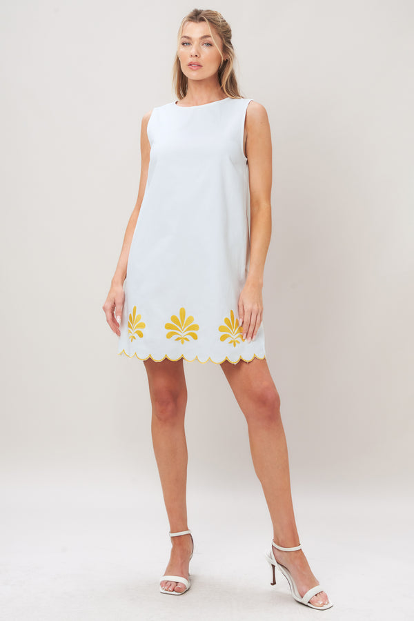 Woman wearing a white dress with yellow floral patterns on a plain background | Flying Tomato