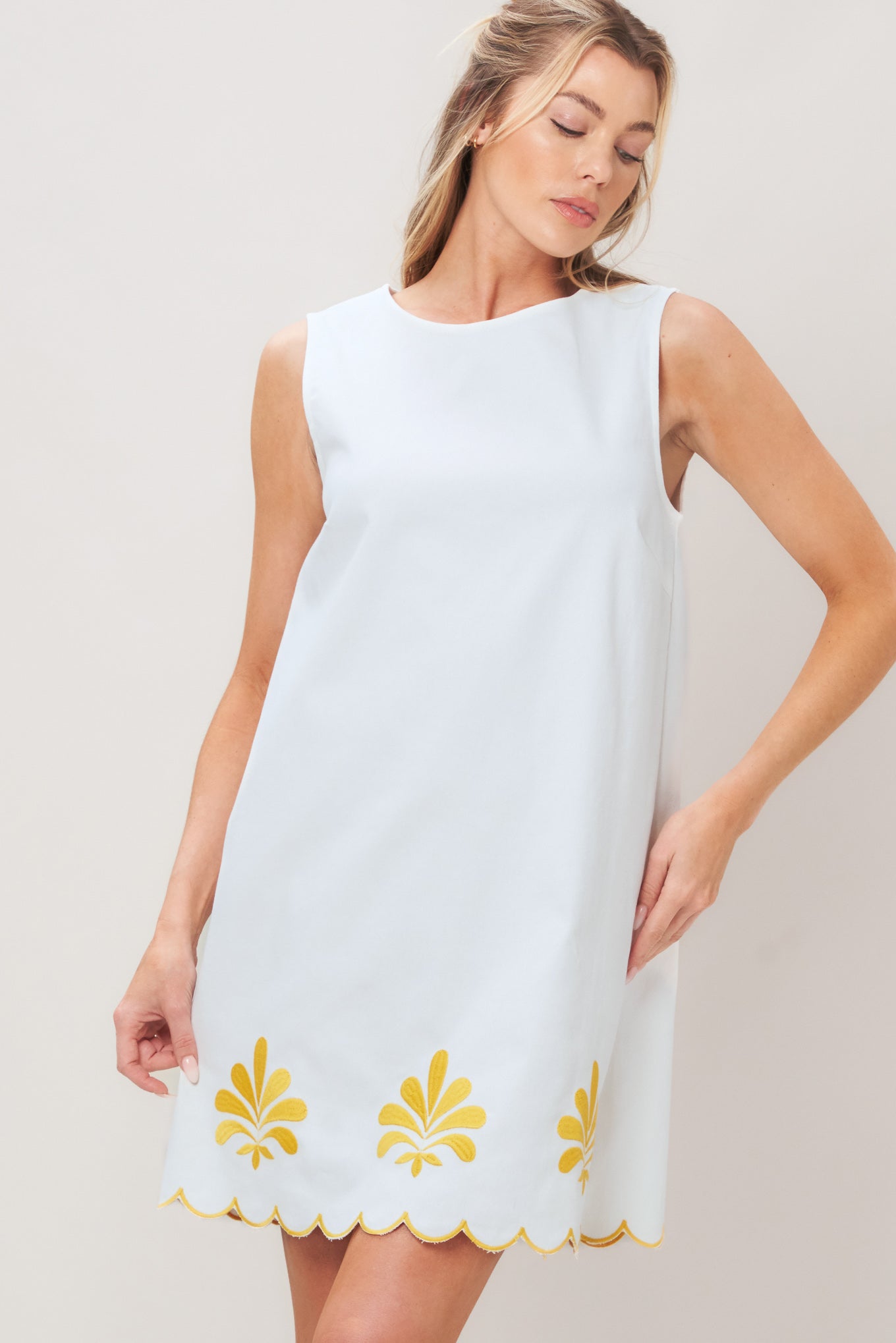 Woman wearing a white dress with yellow floral patterns on a plain background | Flying Tomato