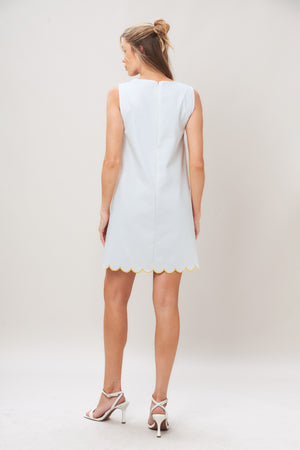 Woman wearing a white dress with yellow floral patterns on a plain background | Flying Tomato