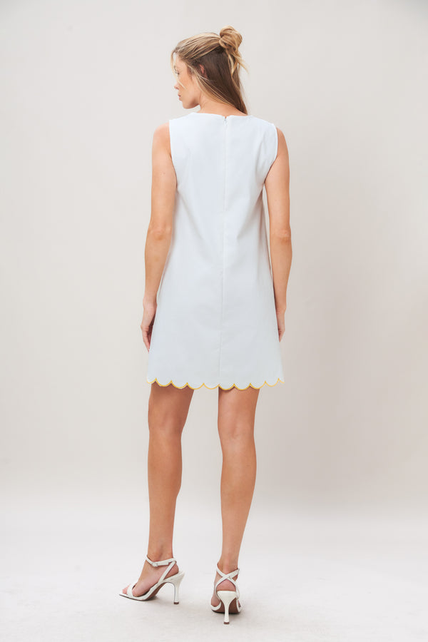 Woman wearing a white dress with yellow floral patterns on a plain background | Flying Tomato