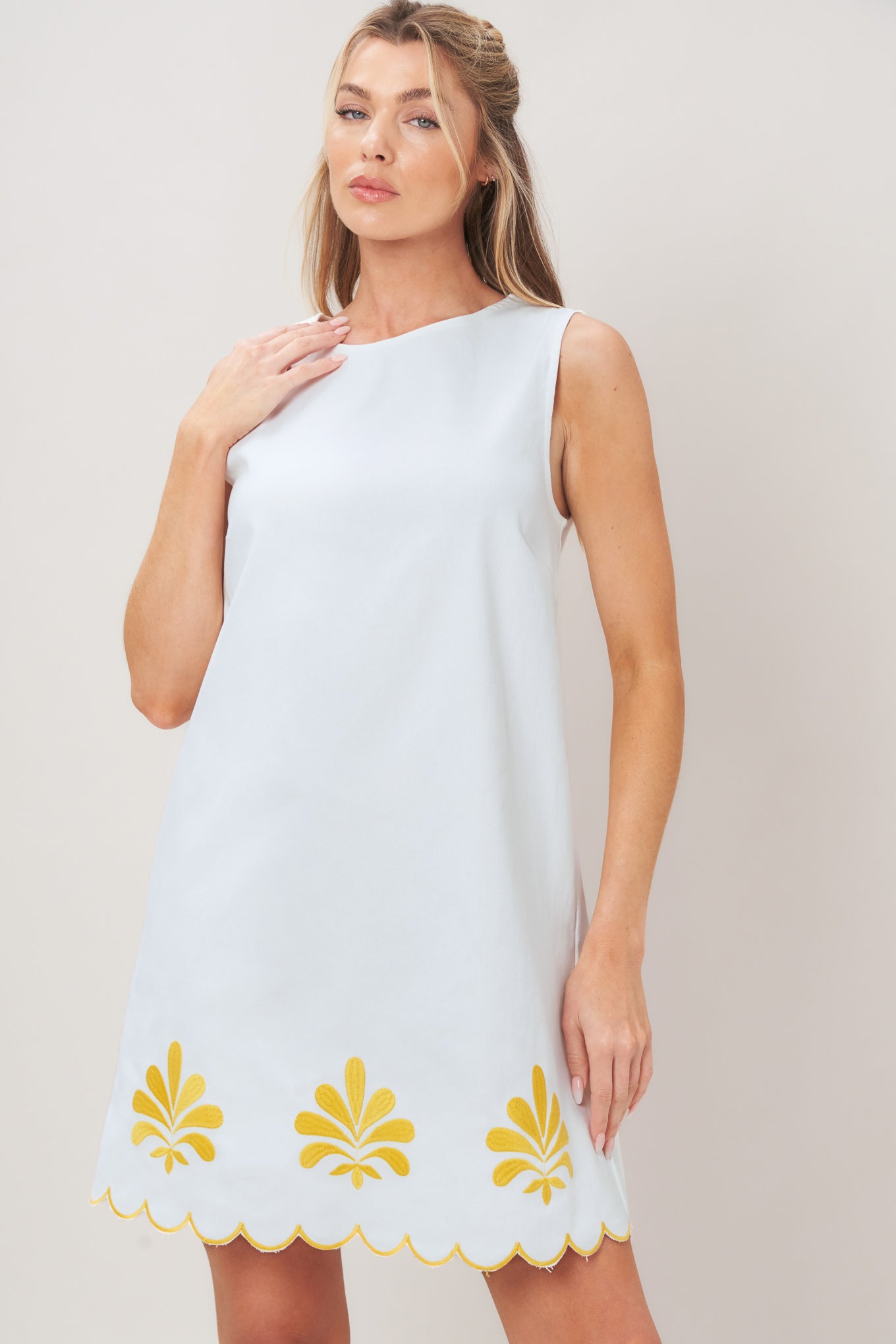 Woman wearing a white dress with yellow floral patterns on a plain background | Flying Tomato