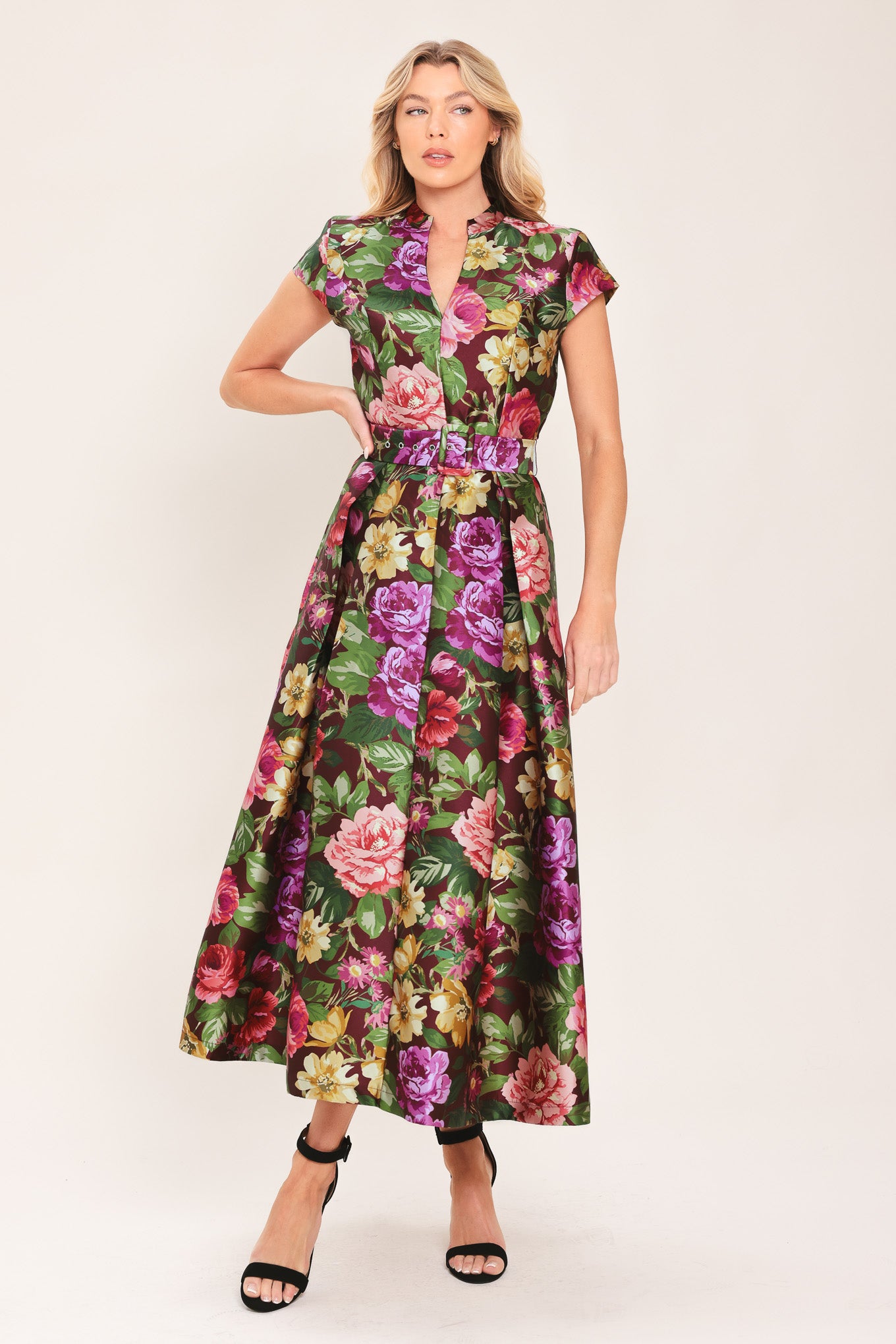 Woman wearing a floral printed woven midi dress featuring high collar with V front, short sleeve, self belt, full skirt and back zipper closure | Flying Tomato