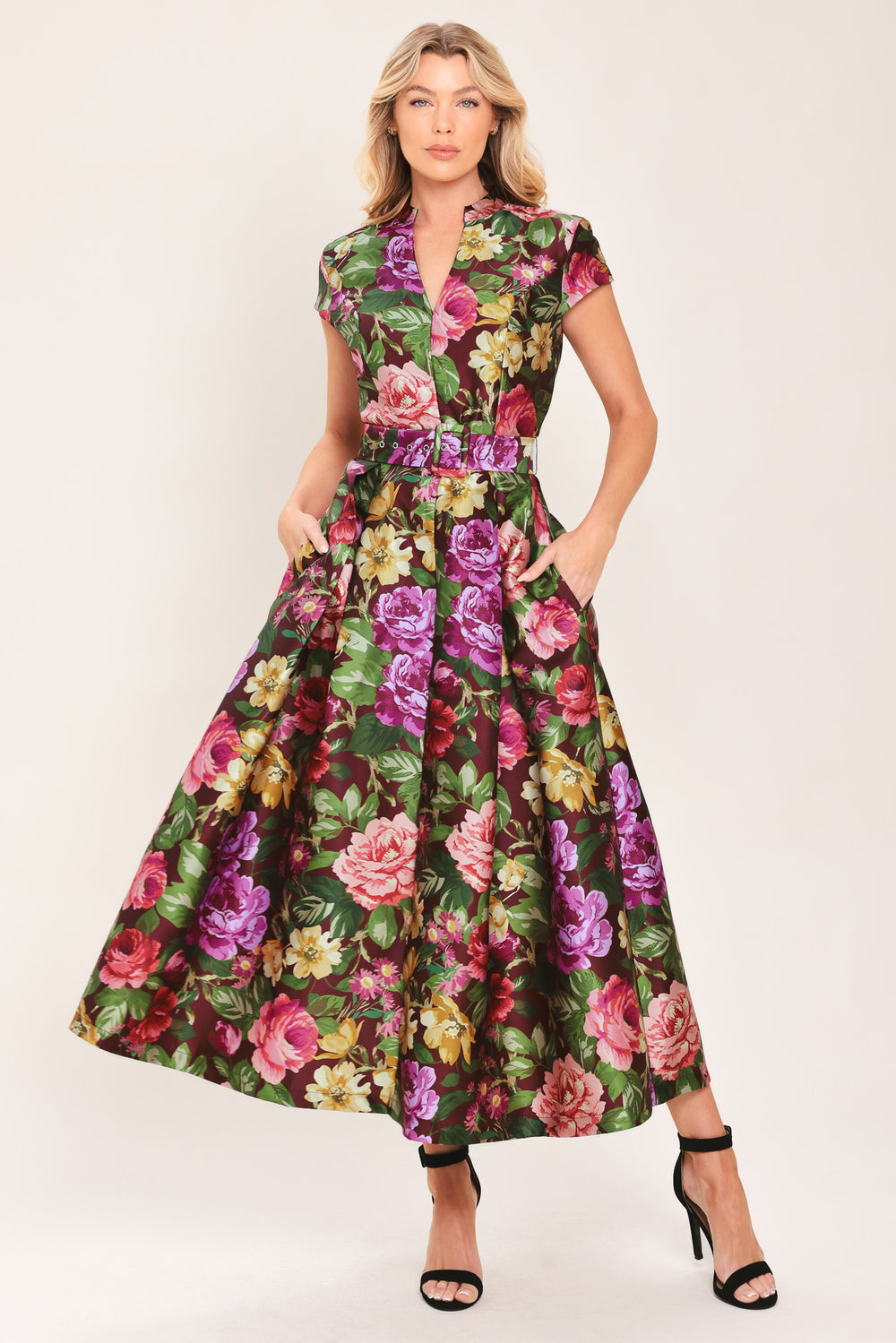 Woman wearing a floral printed woven midi dress featuring high collar with V front, short sleeve, self belt, full skirt and back zipper closure | Flying Tomato
