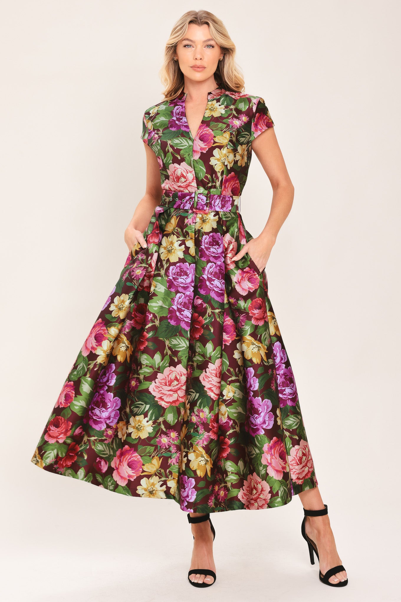 Woman wearing a floral printed woven midi dress featuring high collar with V front, short sleeve, self belt, full skirt and back zipper closure | Flying Tomato