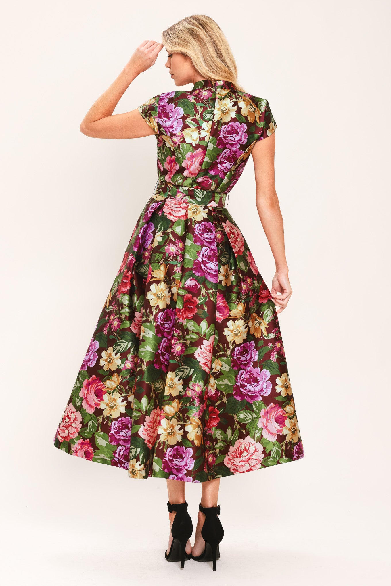 Woman wearing a floral printed woven midi dress featuring high collar with V front, short sleeve, self belt, full skirt and back zipper closure | Flying Tomato
