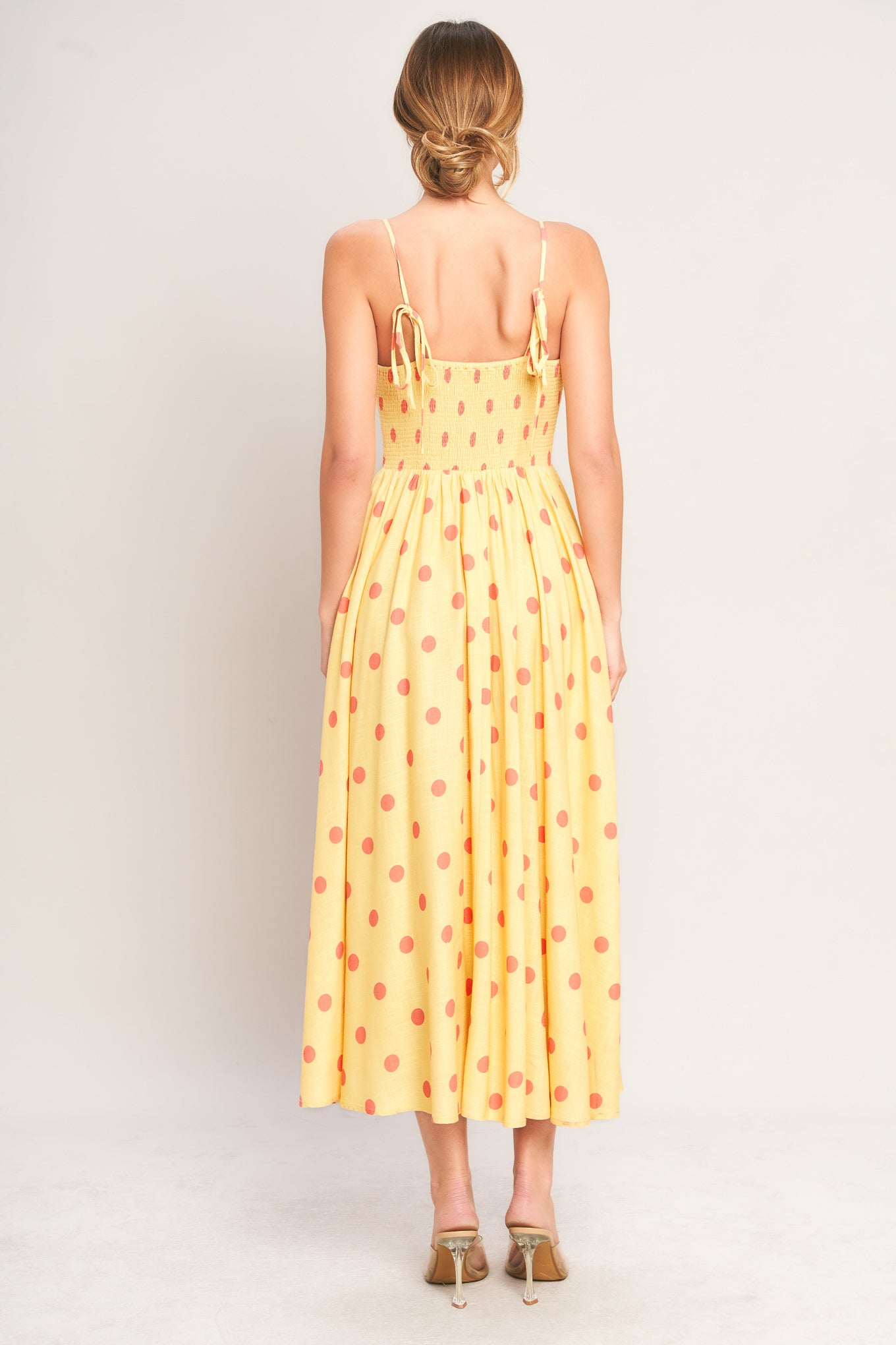 Woman wearing a yellow polka dot dress on a white background