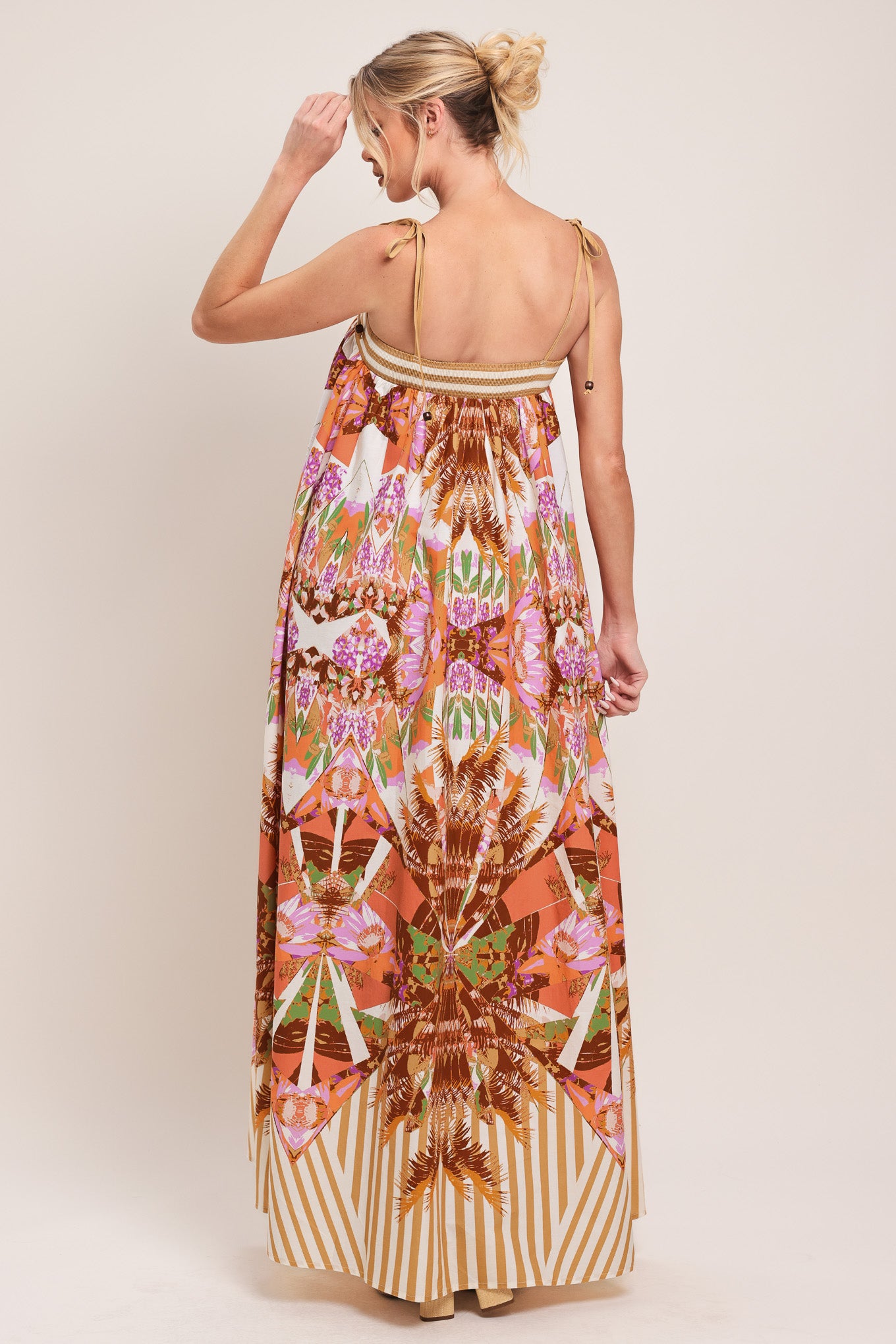 Woman wearing a maxi, patterned, multicolored orange and pink dress | Flying Tomato
