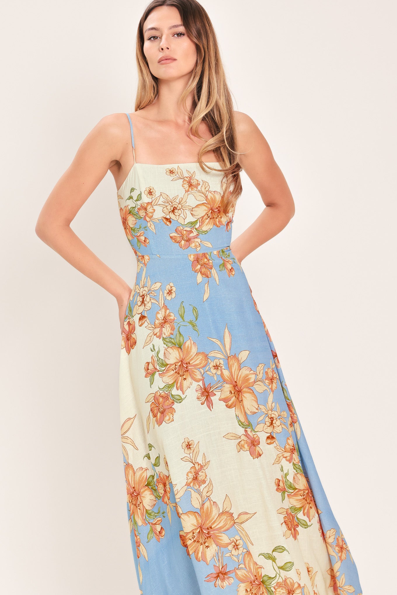 Woman wearing a blue and peach floral midi dress featuring straight neckline, straps, circle skirt and back zipper closure | Flying Tomato