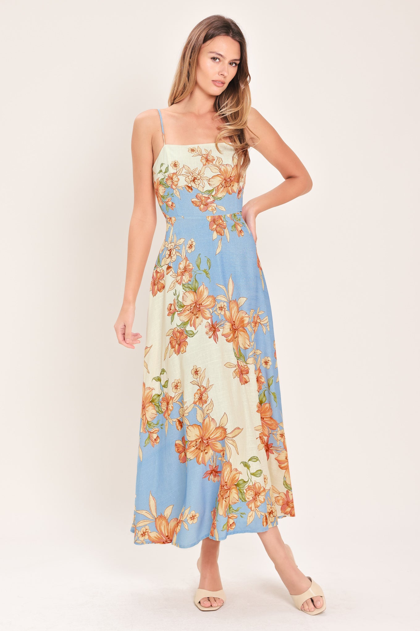 Woman wearing a blue and peach floral midi dress featuring straight neckline, straps, circle skirt and back zipper closure | Flying Tomato