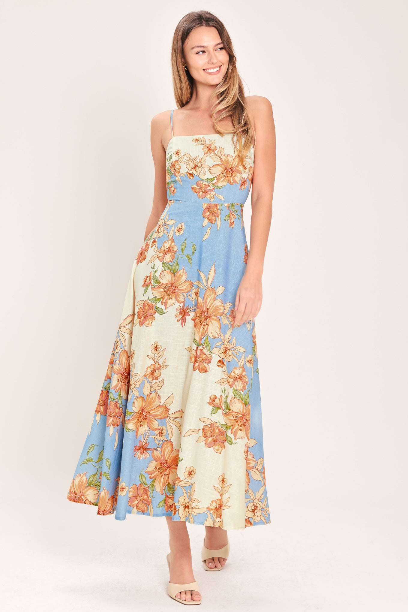 Woman wearing a blue and peach floral midi dress featuring straight neckline, straps, circle skirt and back zipper closure | Flying Tomato