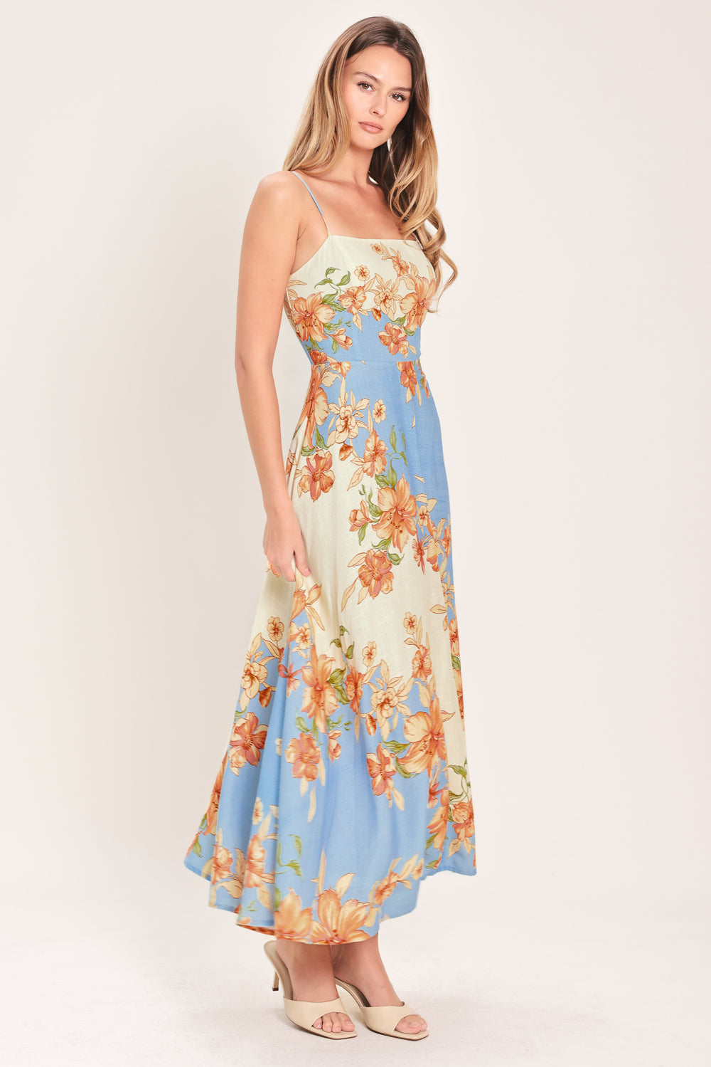 Woman wearing a blue and peach floral midi dress featuring straight neckline, straps, circle skirt and back zipper closure | Flying Tomato