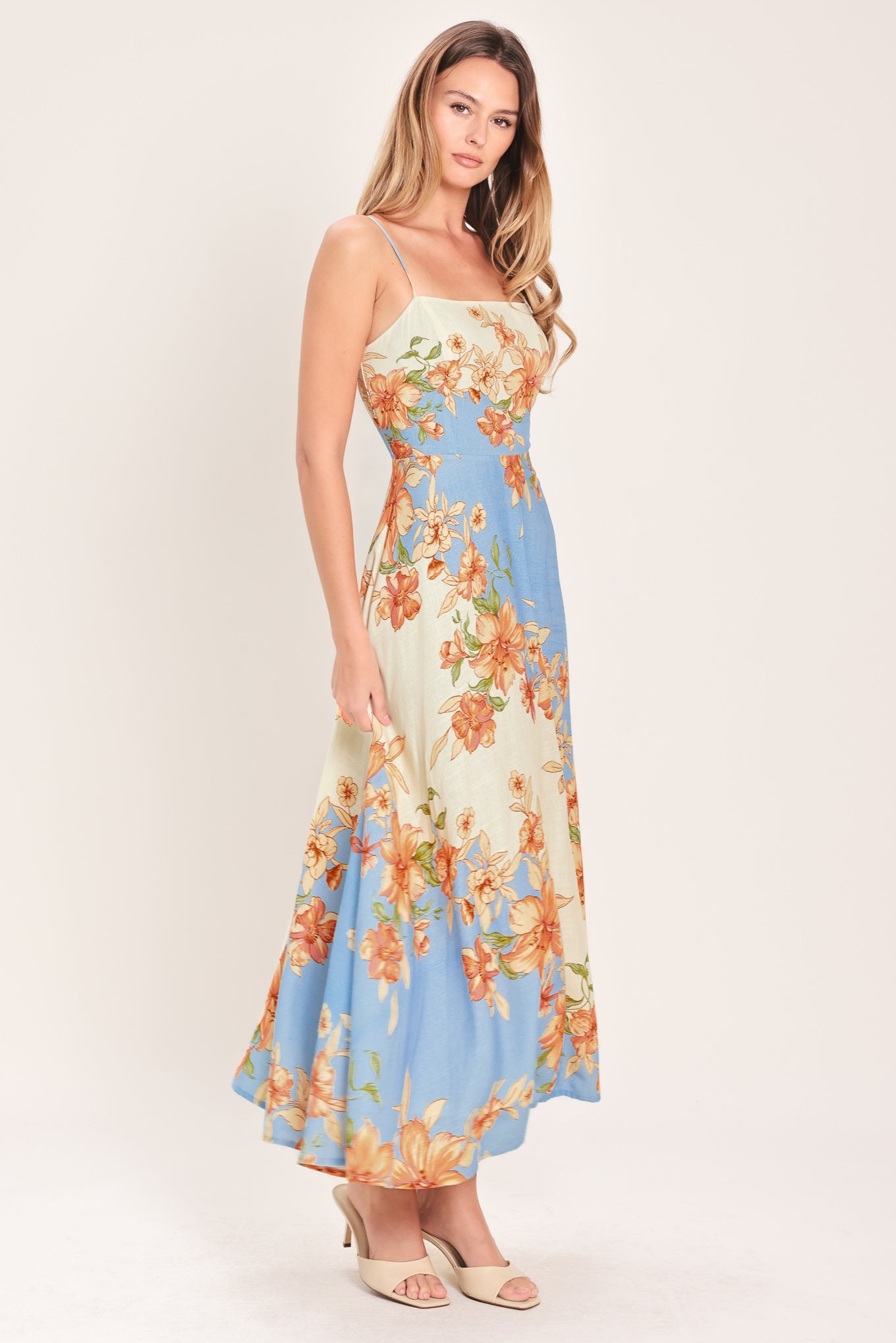 Woman wearing a blue and peach floral midi dress featuring straight neckline, straps, circle skirt and back zipper closure | Flying Tomato