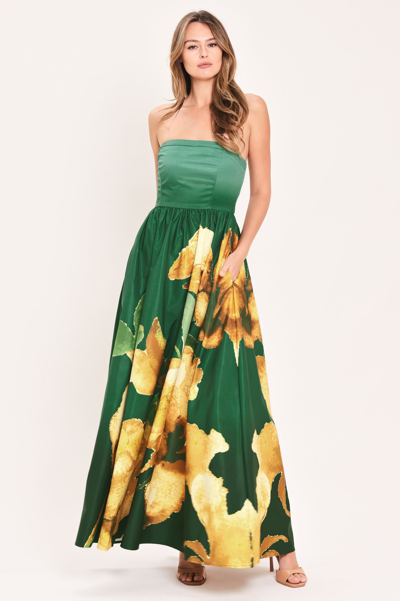 A woman modeling a strapless green maxi dress with a large yellow floral print on the skirt | Flying Tomato