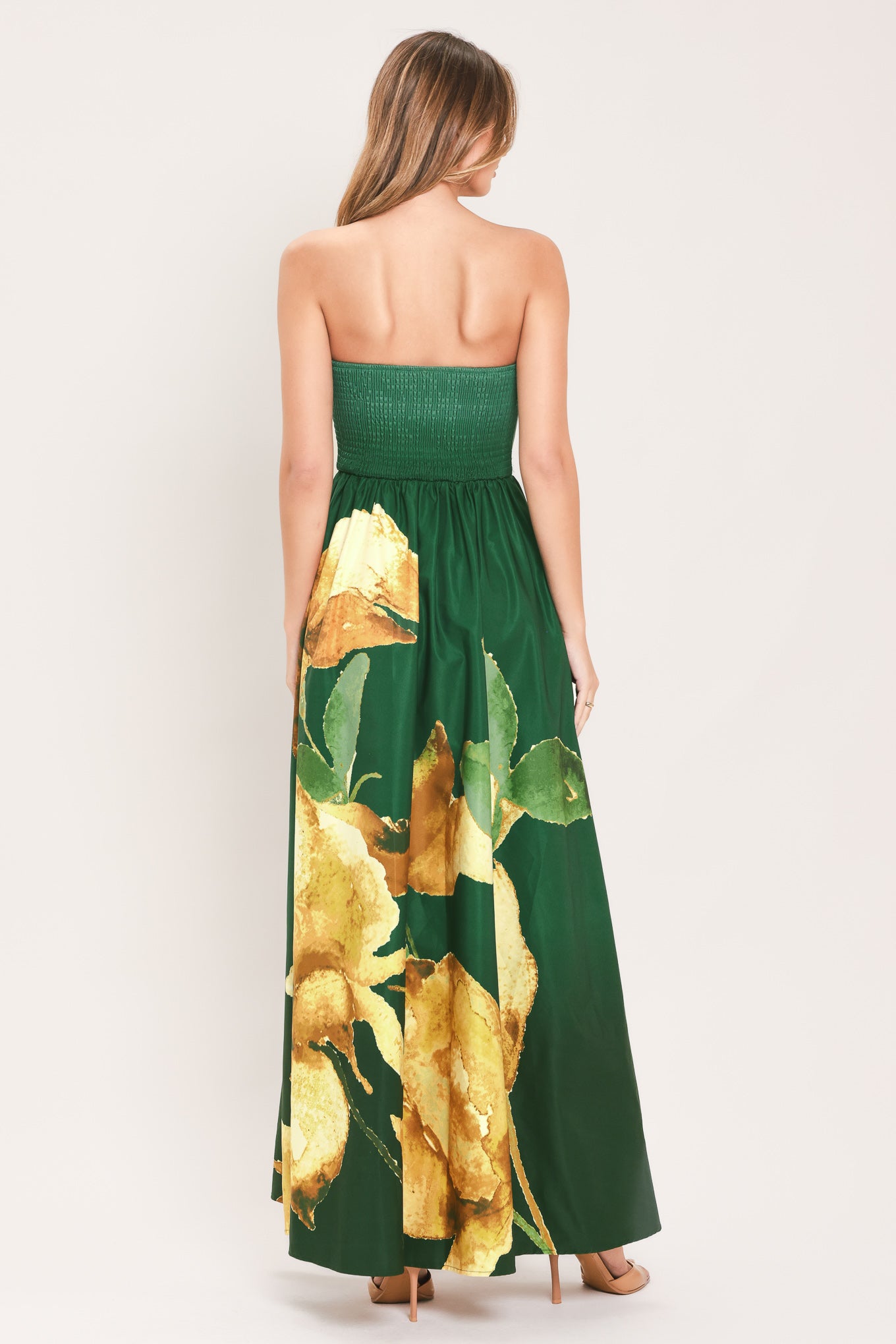 A woman modeling a strapless green maxi dress with a large yellow floral print on the skirt | Flying Tomato