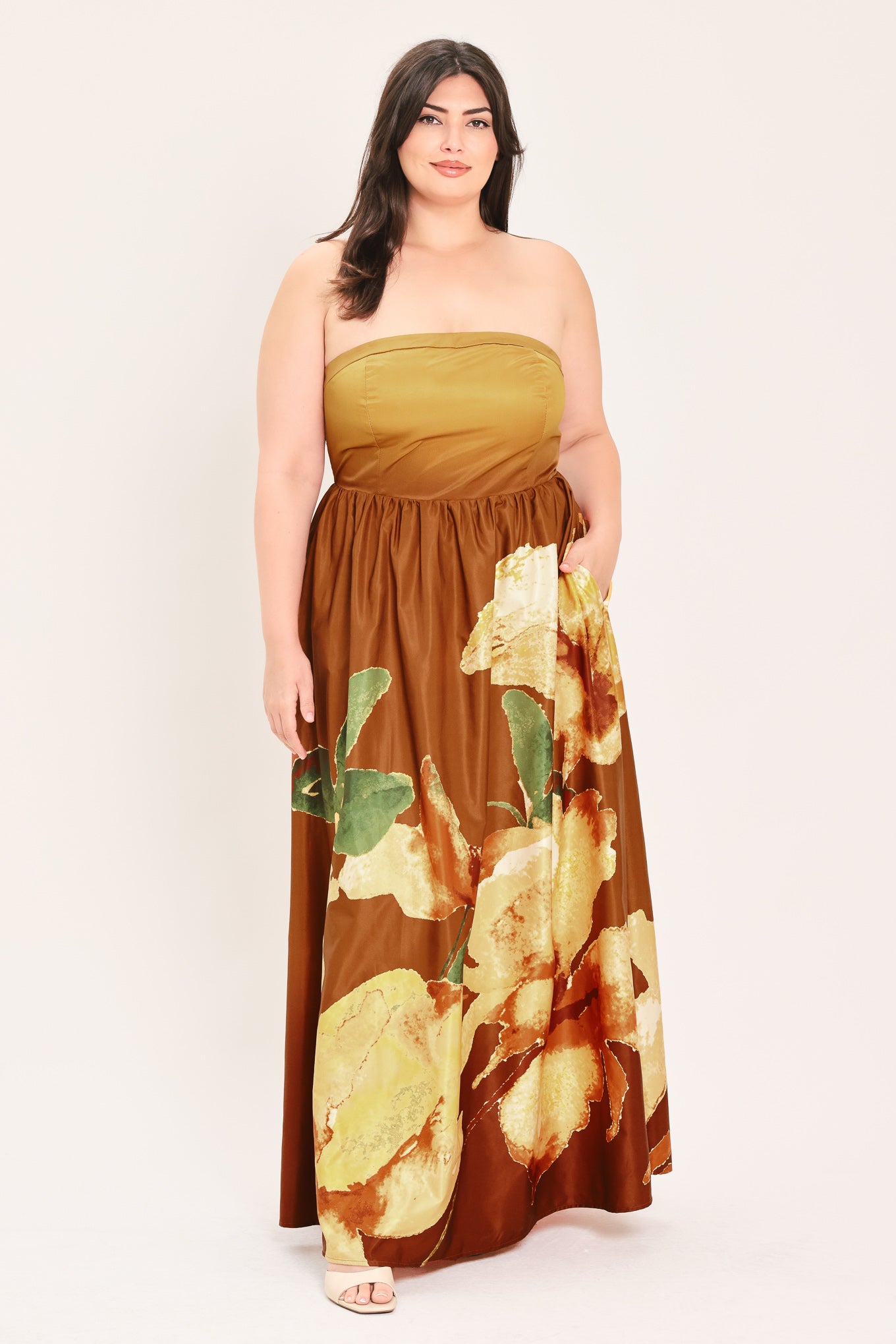 A woman modeling a strapless maxi dress with a mustard yellow top and a brown skirt featuring a large yellow and green floral print | Flying Tomato Curve
