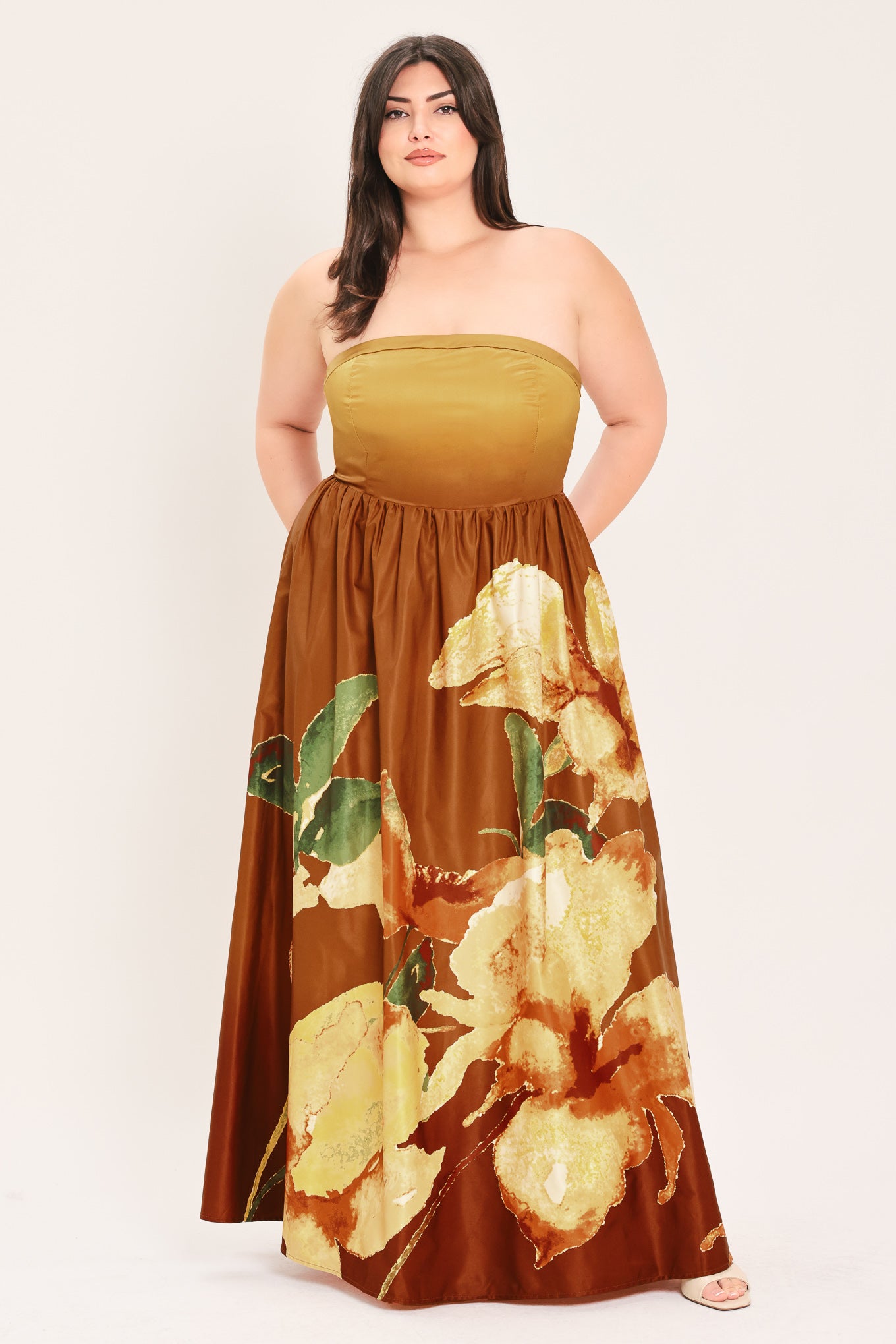 A woman modeling a strapless maxi dress with a mustard yellow top and a brown skirt featuring a large yellow and green floral print | Flying Tomato Curve