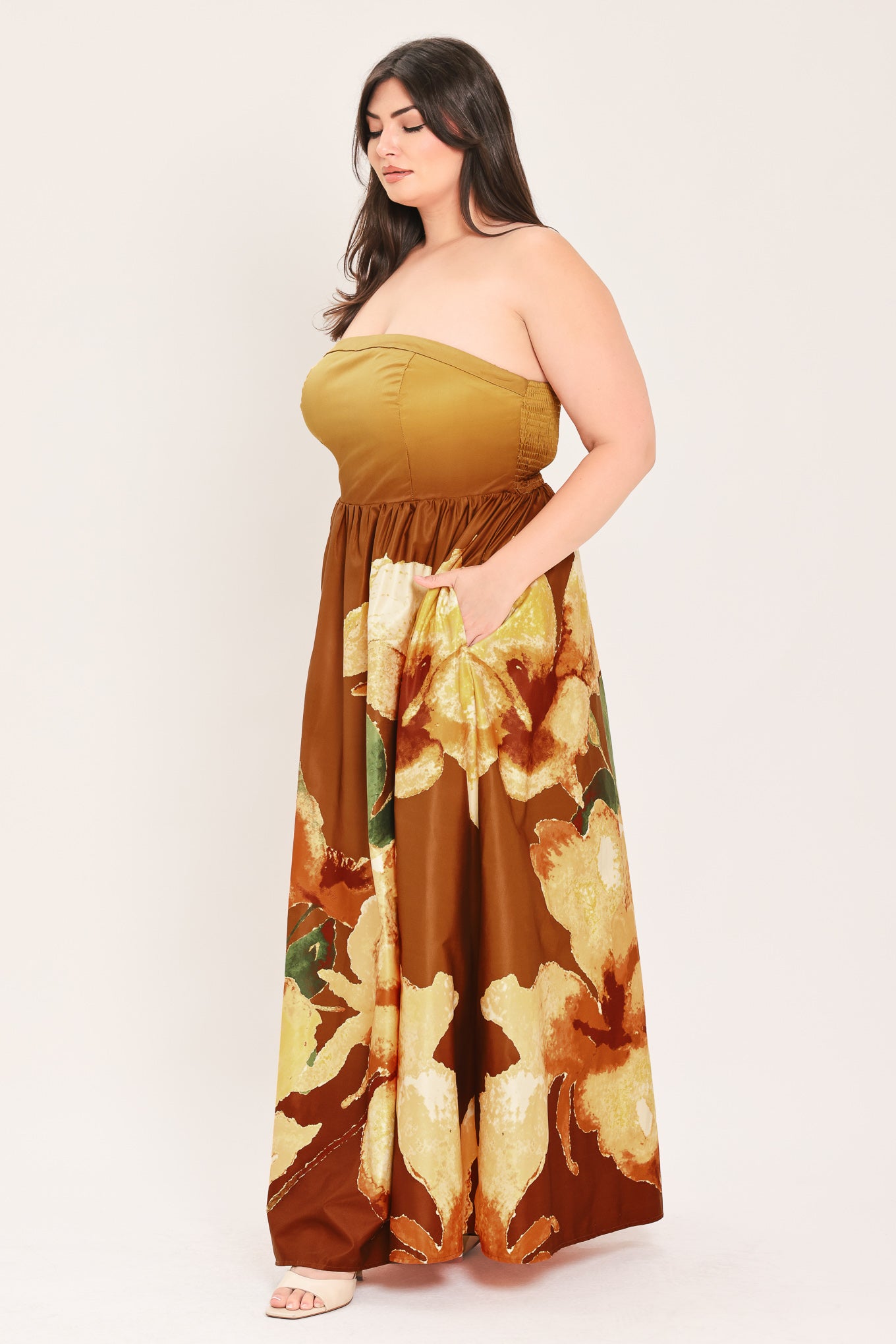 A woman modeling a strapless maxi dress with a mustard yellow top and a brown skirt featuring a large yellow and green floral print | Flying Tomato Curve