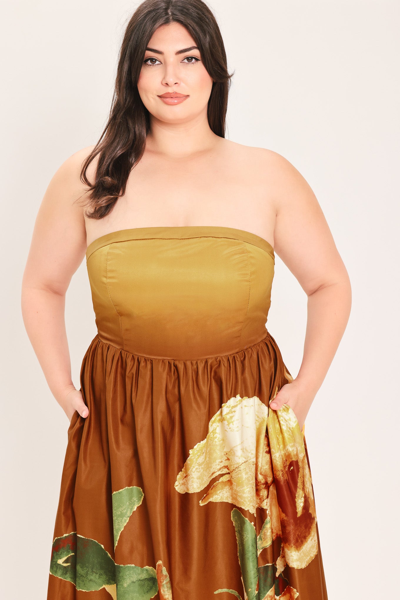 A woman modeling a strapless maxi dress with a mustard yellow top and a brown skirt featuring a large yellow and green floral print | Flying Tomato Curve