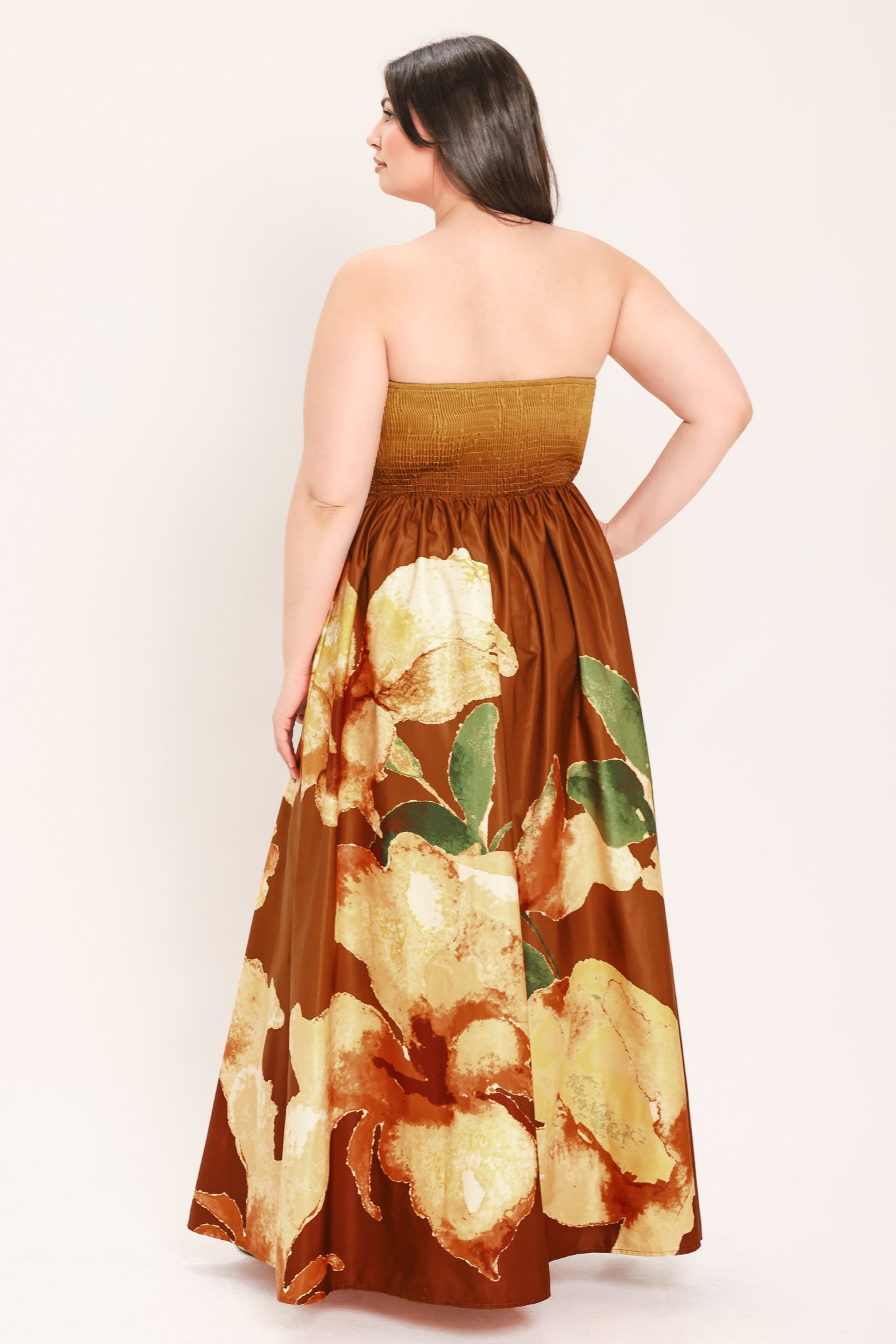 A woman modeling a strapless maxi dress with a mustard yellow top and a brown skirt featuring a large yellow and green floral print | Flying Tomato Curve