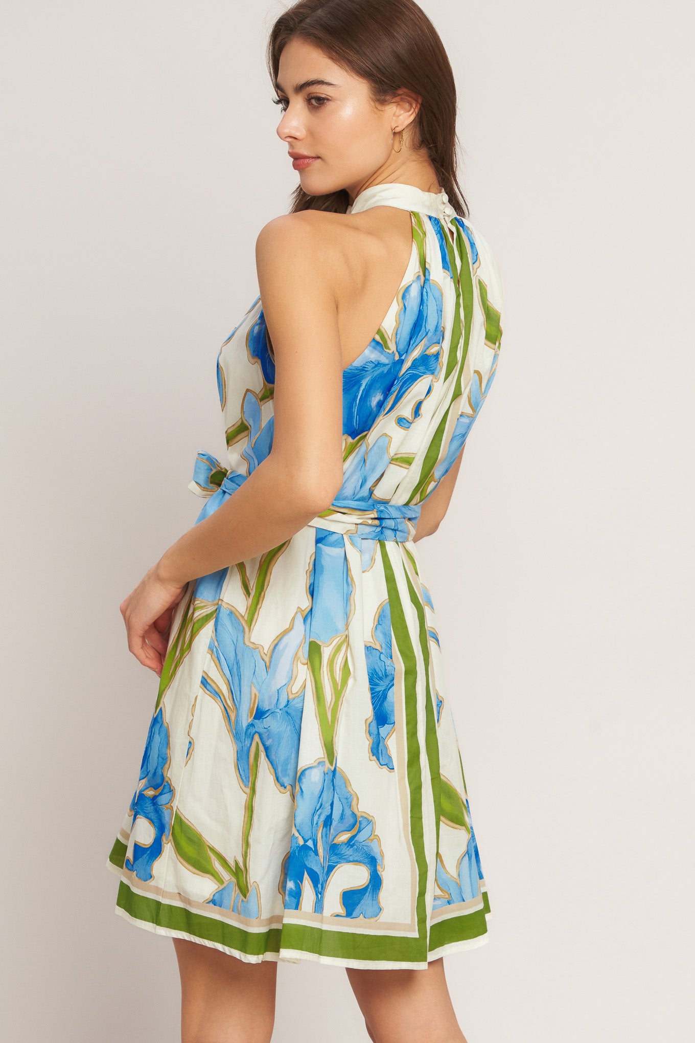 Woman wearing a floral dress with blue and green patterns on a plain background
