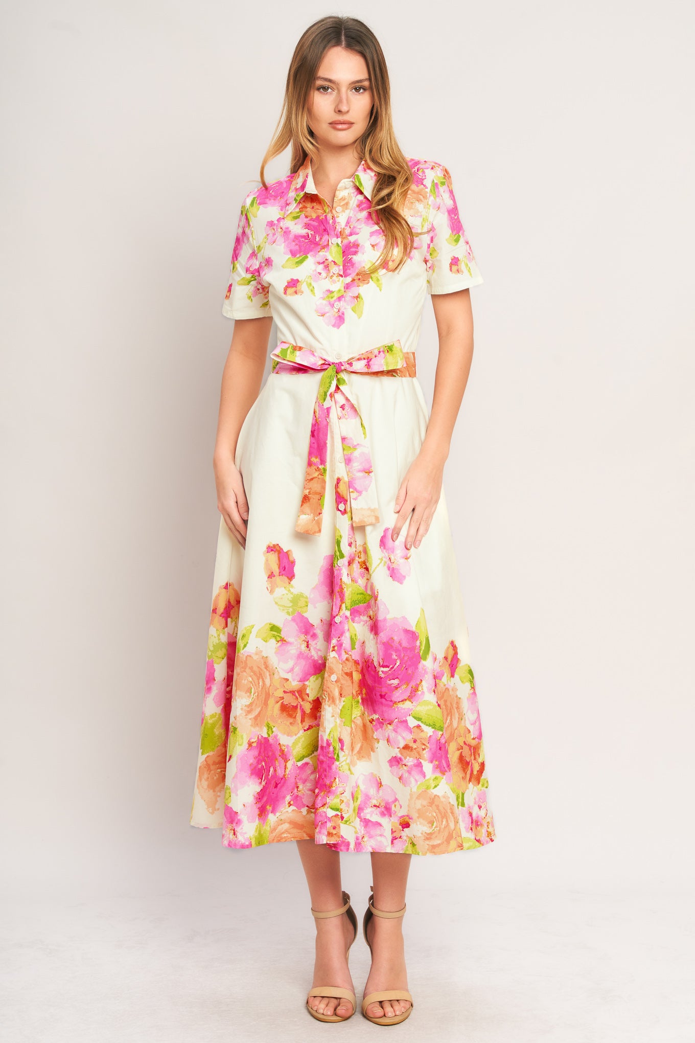 Woman wearing a floral dress with a belt on a plain background