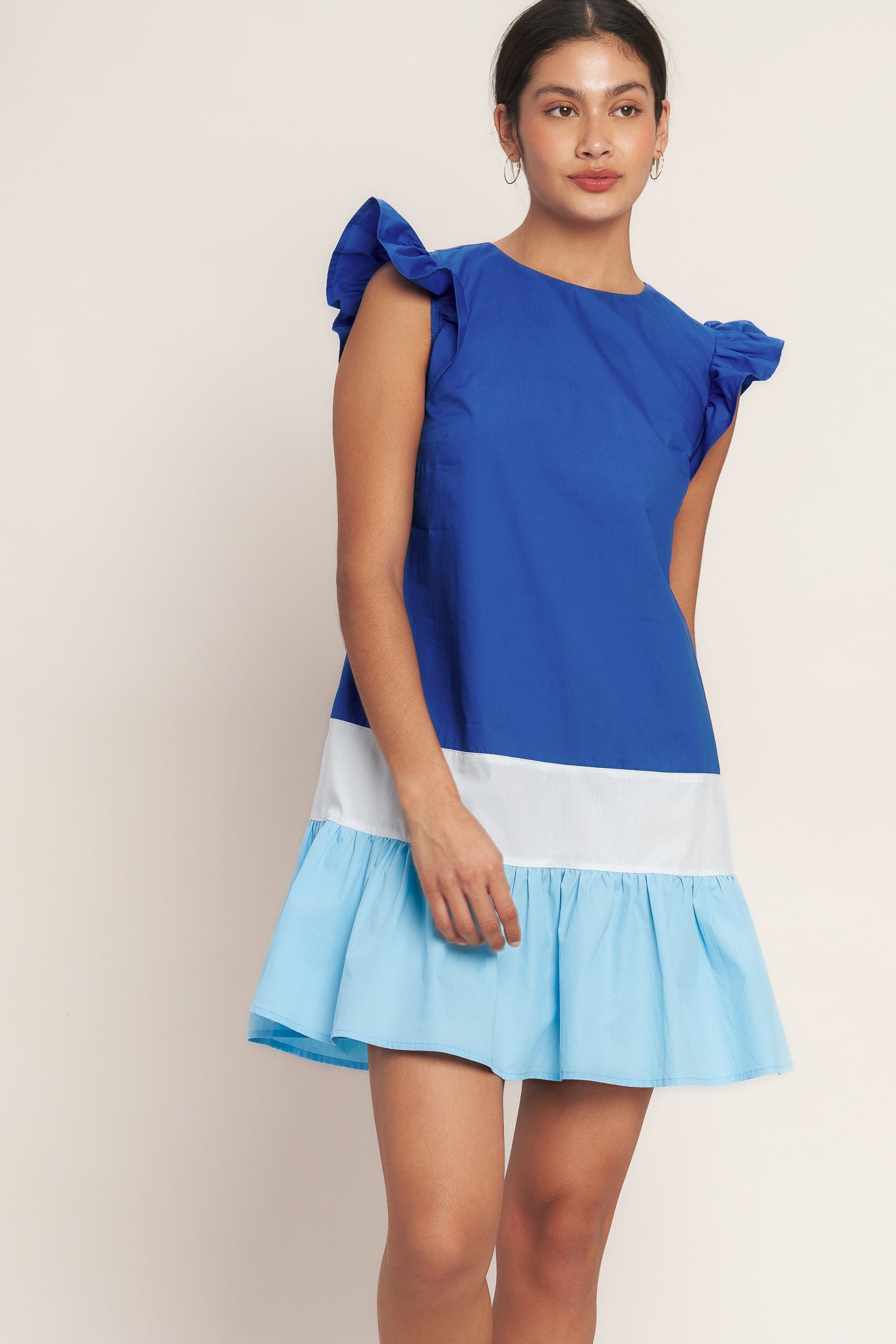 
A woven color blocked mini dress featuring round neckline, ruffle sleeve, ruffle hem and back neck button closure

Details:

Self : 100% Cotton
Contrast : 100% Cotton

Size &amp; Fit

- Model is 5`8" And Wearing Size Small
- Measurements Taken From Size Small
- Approx. Length: 35"
