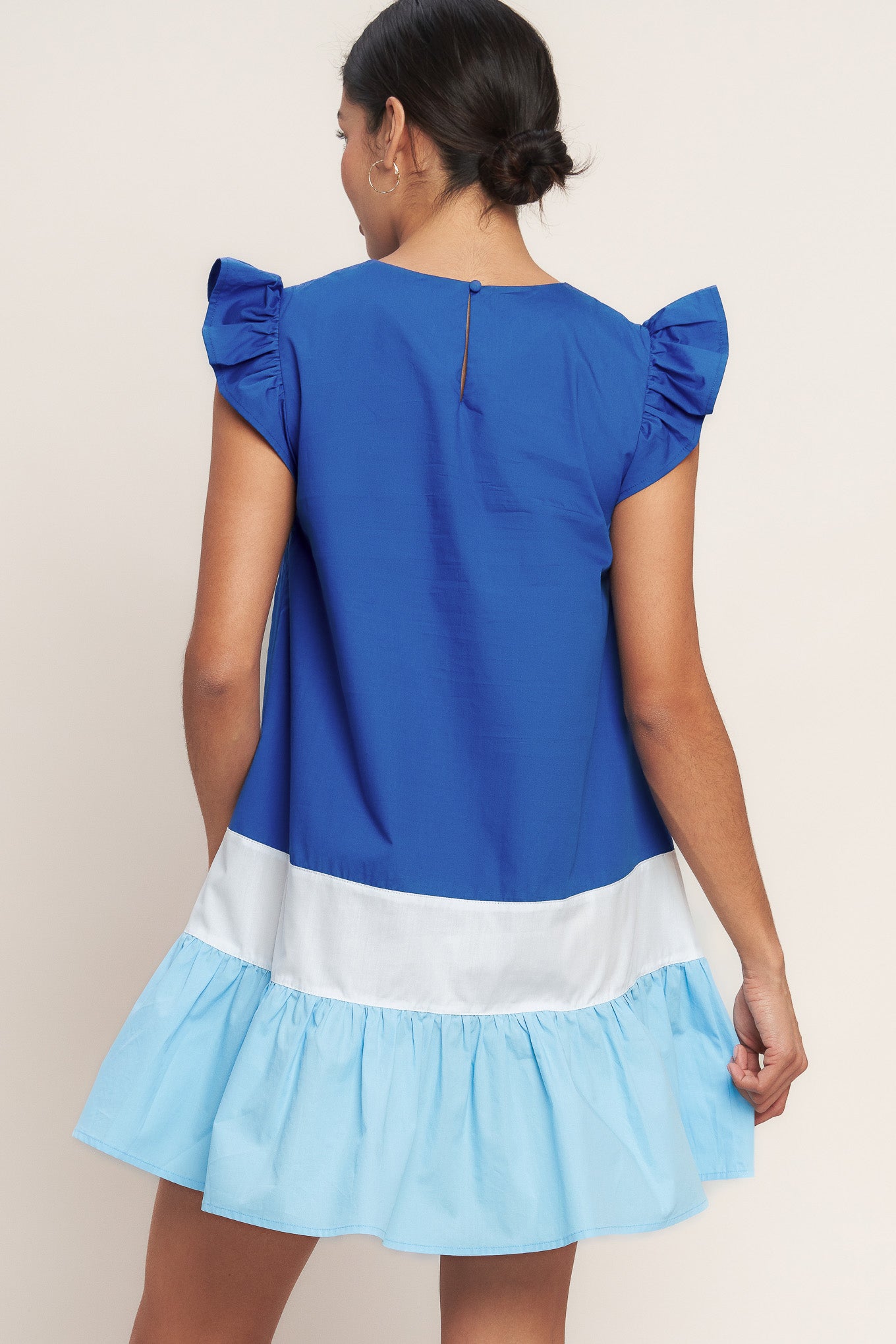 
A woven color blocked mini dress featuring round neckline, ruffle sleeve, ruffle hem and back neck button closure

Details:

Self : 100% Cotton
Contrast : 100% Cotton

Size &amp; Fit

- Model is 5`8" And Wearing Size Small
- Measurements Taken From Size Small
- Approx. Length: 35"