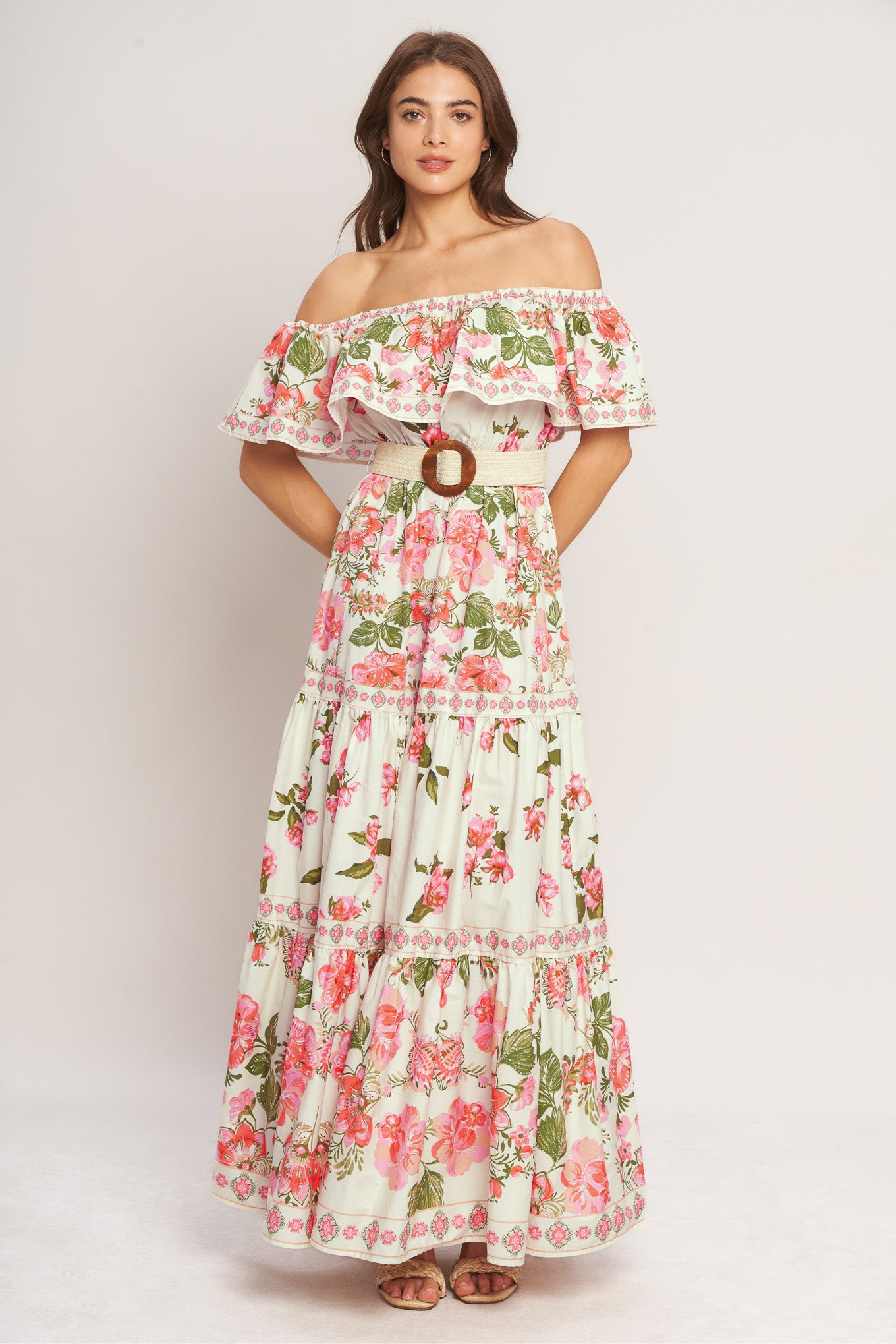 A printed maxi dress featuring off shoulder neckline with flounce, elasticized waist, contrasting belt and tiered skirt