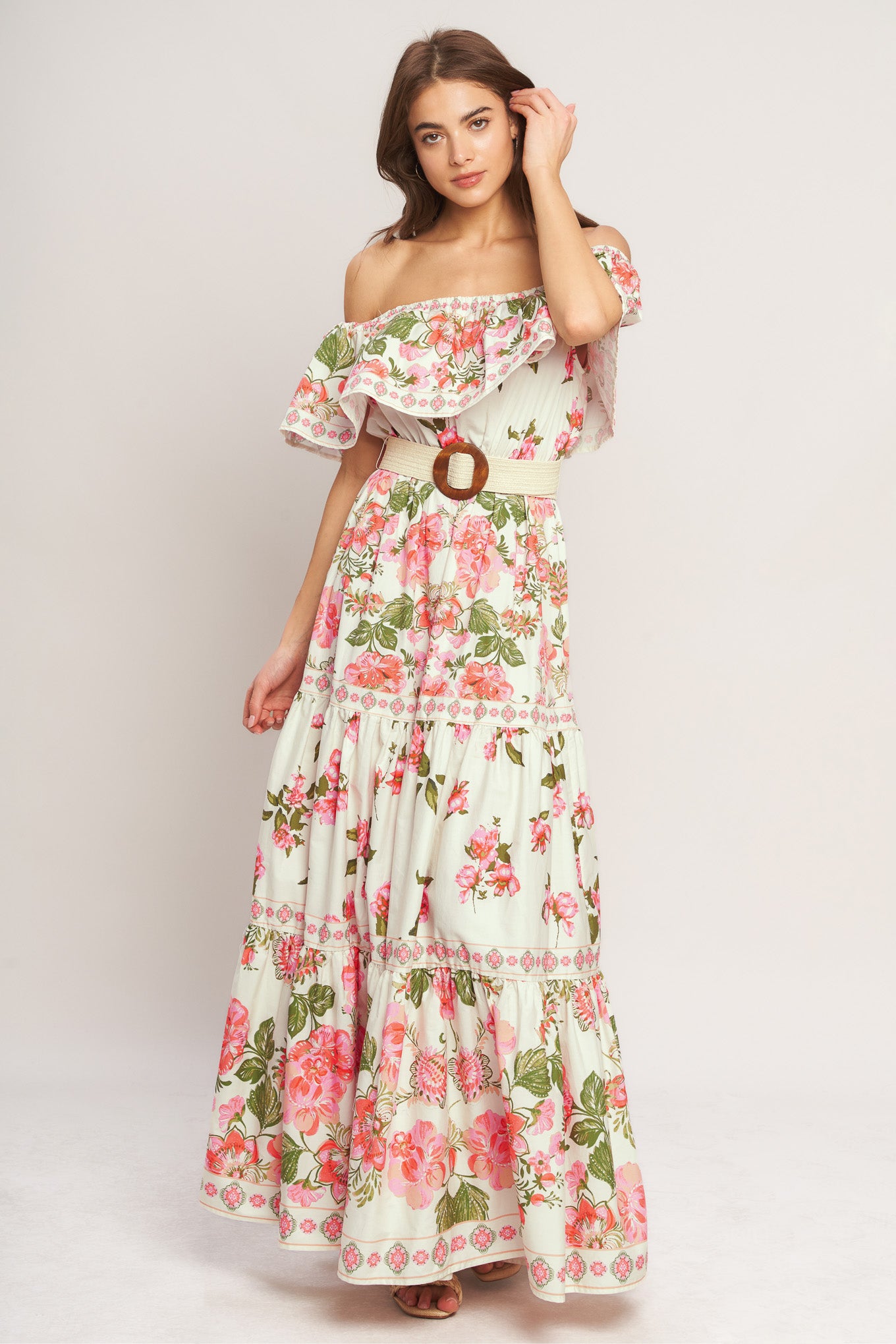 A printed maxi dress featuring off shoulder neckline with flounce, elasticized waist, contrasting belt and tiered skirt