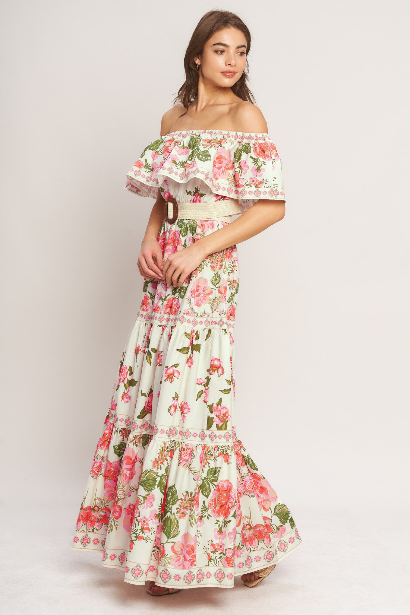 A printed maxi dress featuring off shoulder neckline with flounce, elasticized waist, contrasting belt and tiered skirt