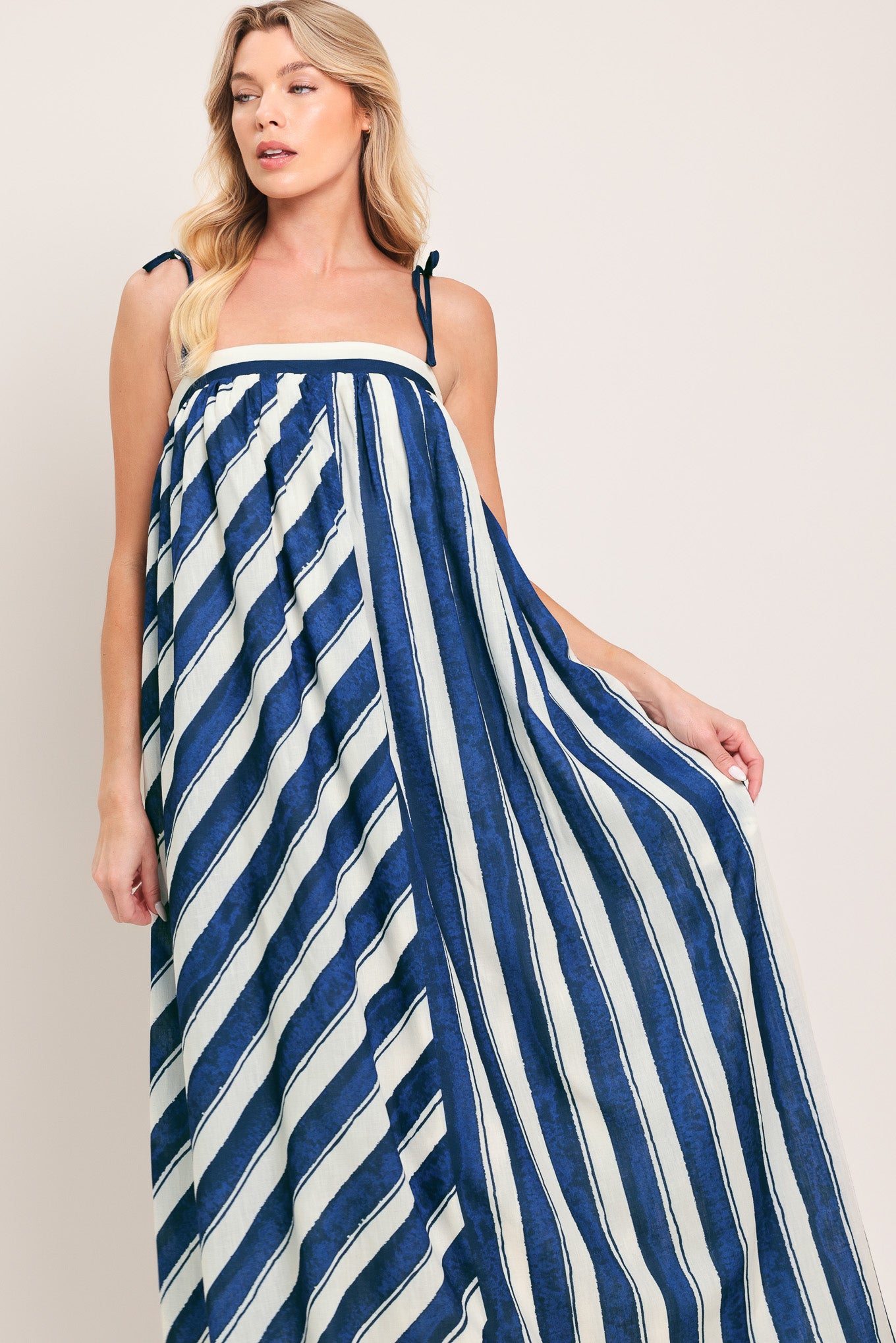 Woman wearing a blue and white striped maxi dress with shoulder ties and smocked back band | Flying Tomato