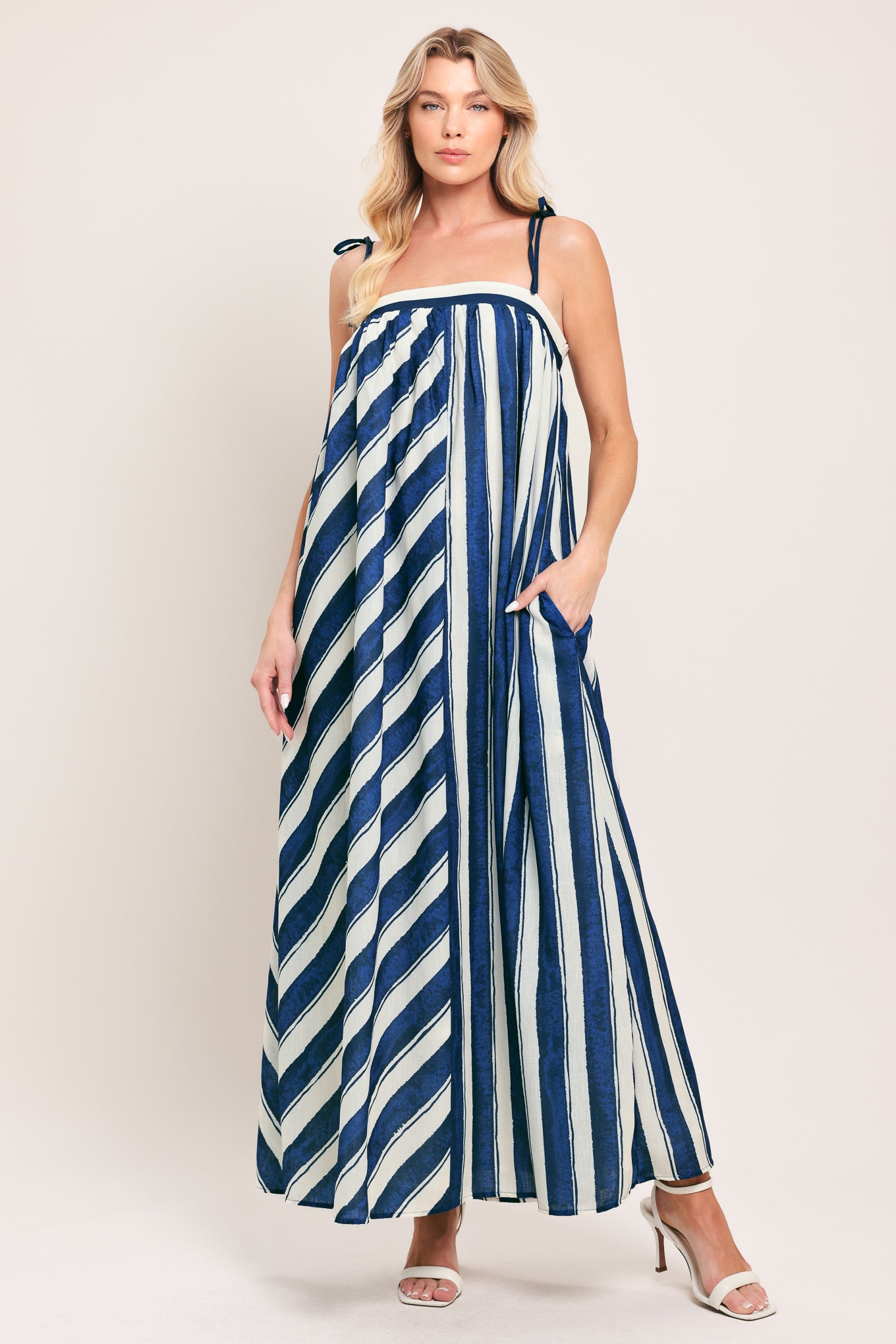 Woman wearing a blue and white striped maxi dress with shoulder ties and smocked back band | Flying Tomato
