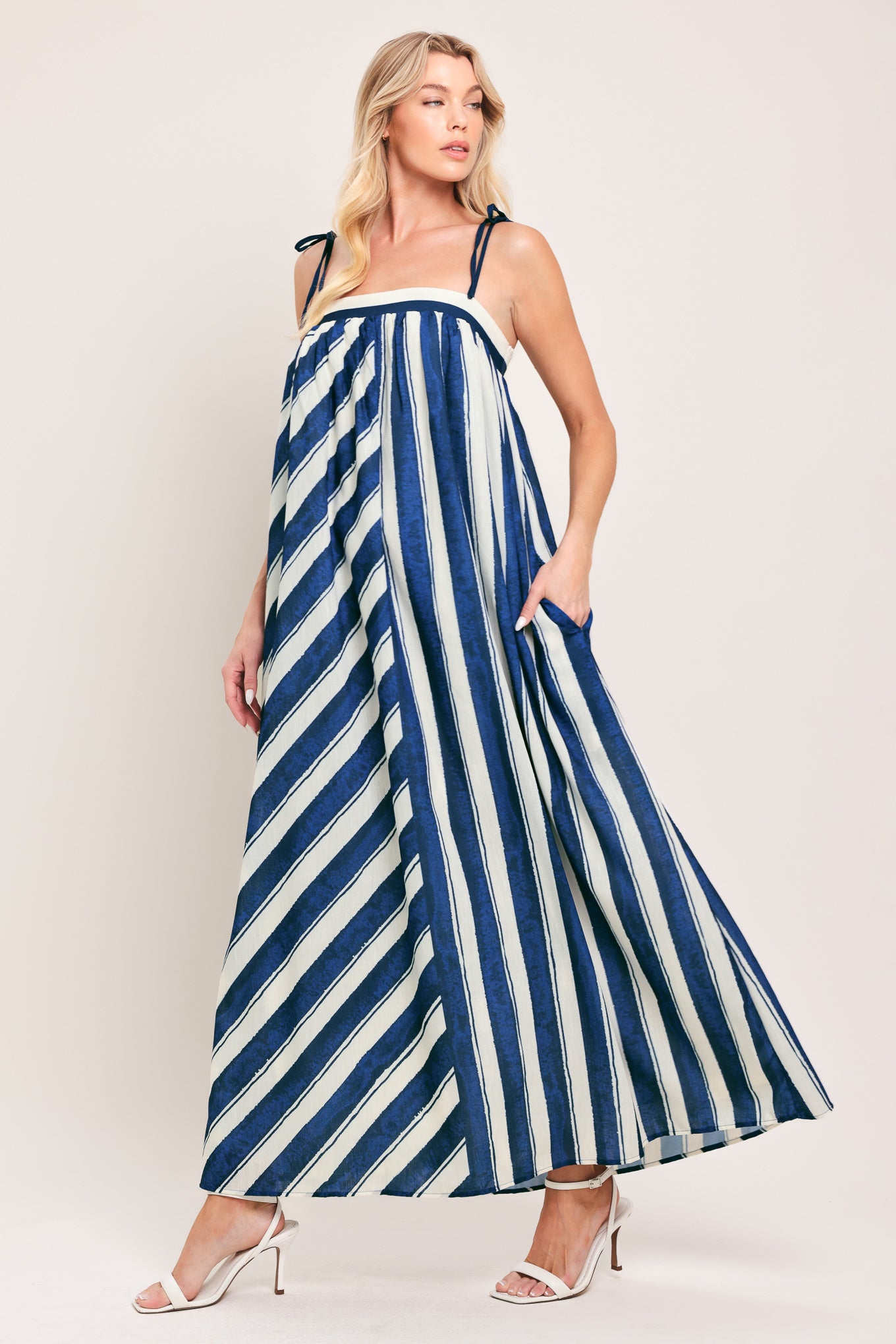 Woman wearing a blue and white striped maxi dress with shoulder ties and smocked back band | Flying Tomato