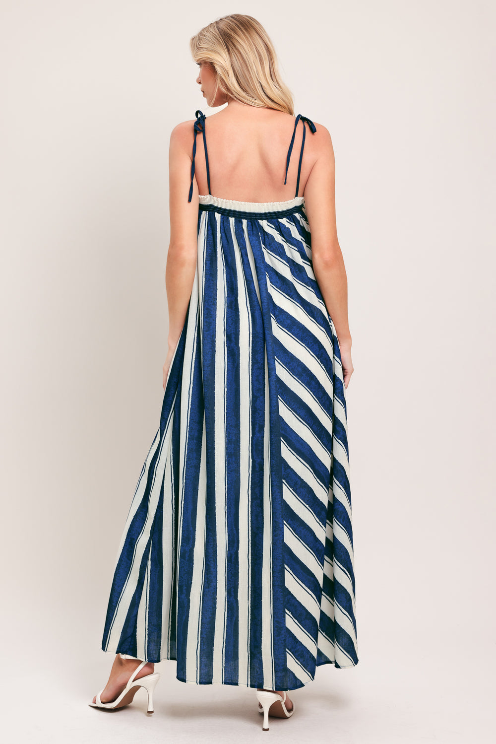 Woman wearing a blue and white striped maxi dress with shoulder ties and smocked back band | Flying Tomato