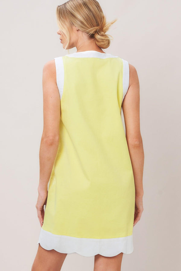Woman wearing a yellow with white trim mini dress featuring round neckline, sleeveless, front button down and scallop hem