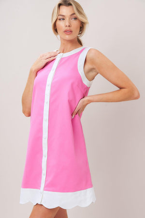 Woman wearing a pink with white trim mini dress featuring round neckline, sleeveless, front button down and scallop hem