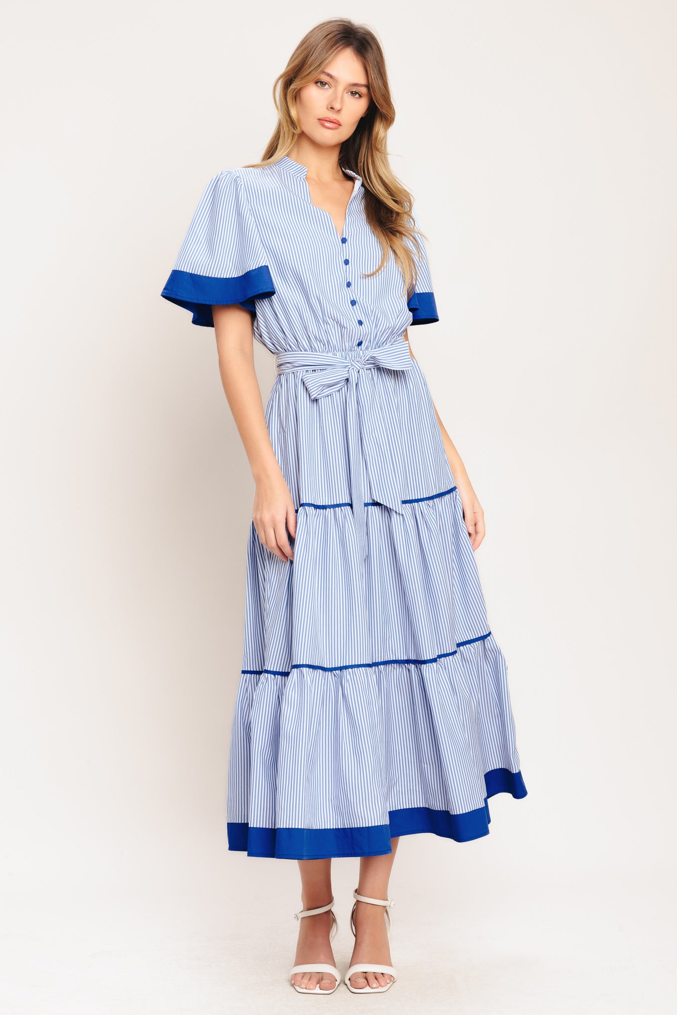 A striped woven midi dress featuring high neckline with V front, short flutter sleeve, button down bodice, elasticized waist with self sash tie and tiered skirt

Details:

Self: 100% Polyester

Contrast: 100% Cotton

Lining: 100% Polyester

Size & Fit

-Model is 5`8" And Wearing Size Small
-Measurements Taken From Size Small
-Approx. Length: 54"