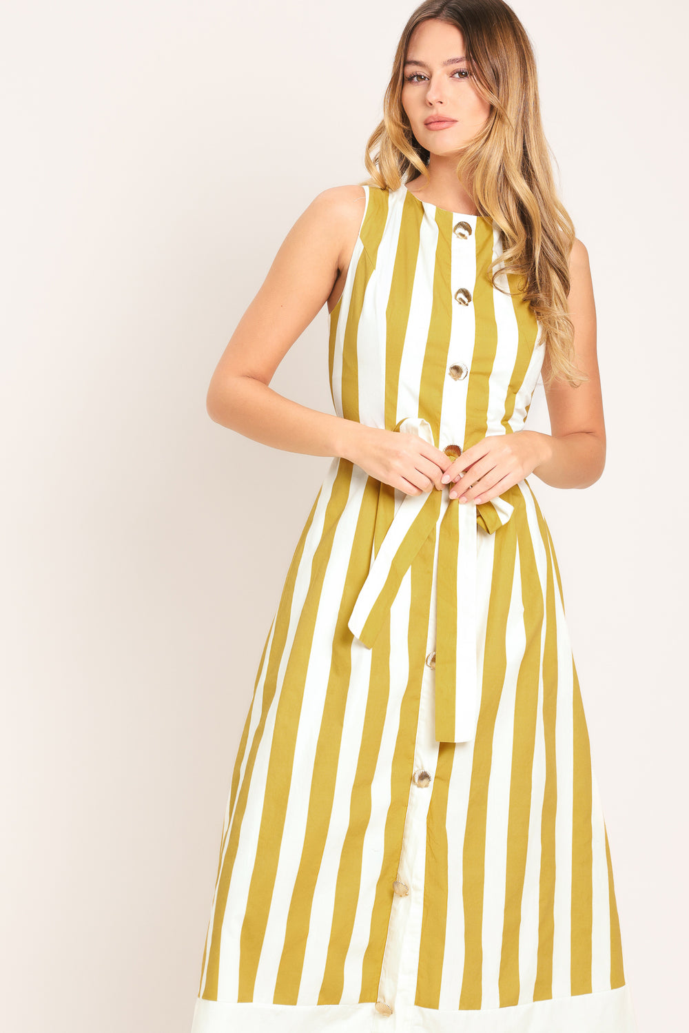 Woman wearing a yellow and white striped midi dress featuring round neckline, sleeveless, self sash tie, full skirt and back zipper closure | Flying Tomato