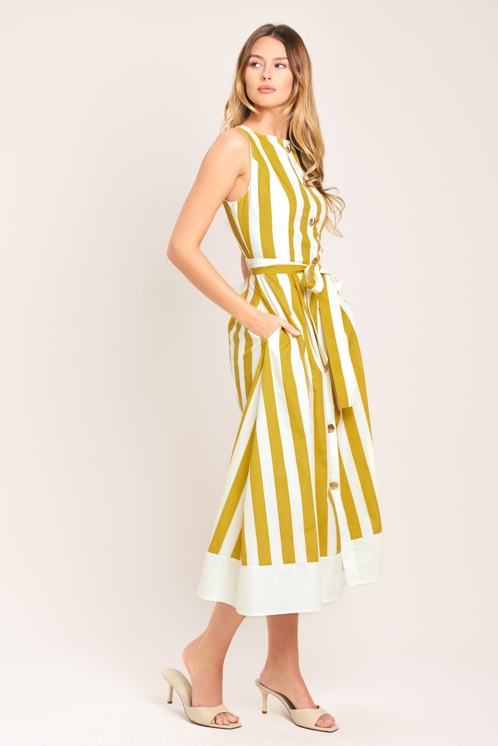 Woman wearing a yellow and white striped midi dress featuring round neckline, sleeveless, self sash tie, full skirt and back zipper closure | Flying Tomato