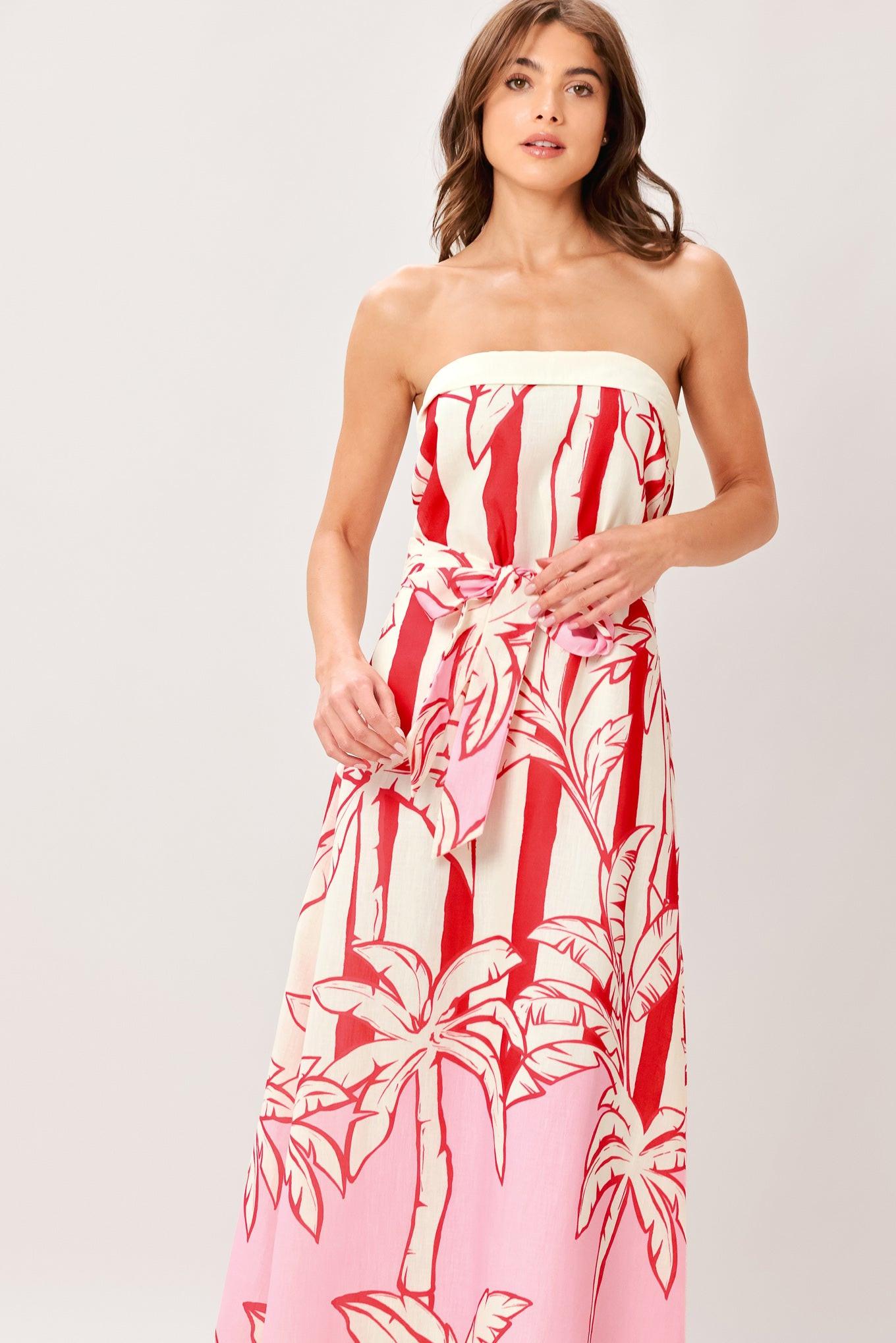 Woman wearing a red and white palm tree pattern printed woven ankle dress featuring strapless, front fold, self sash and back zipper closure